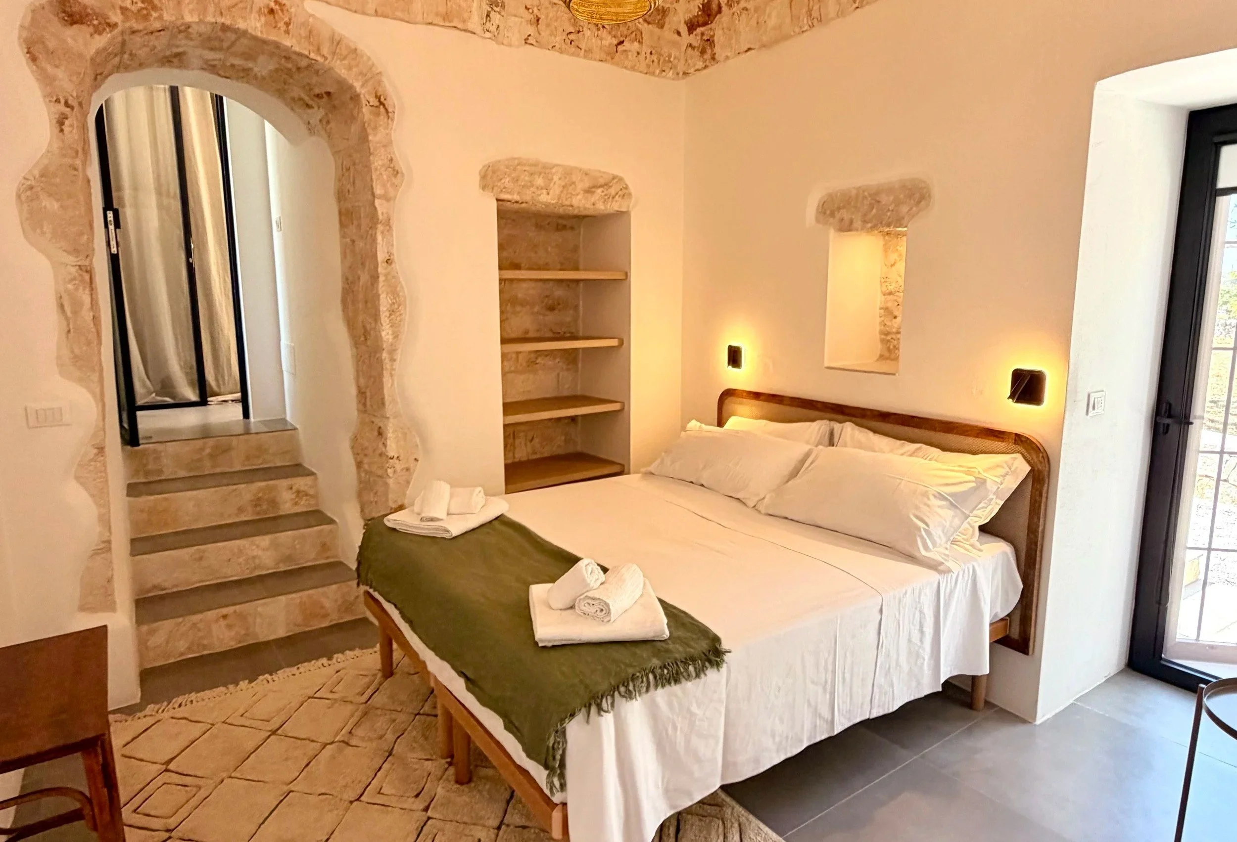 Bedroom with whitewashed stone arches and steps at Trullo Ostro, Puglia