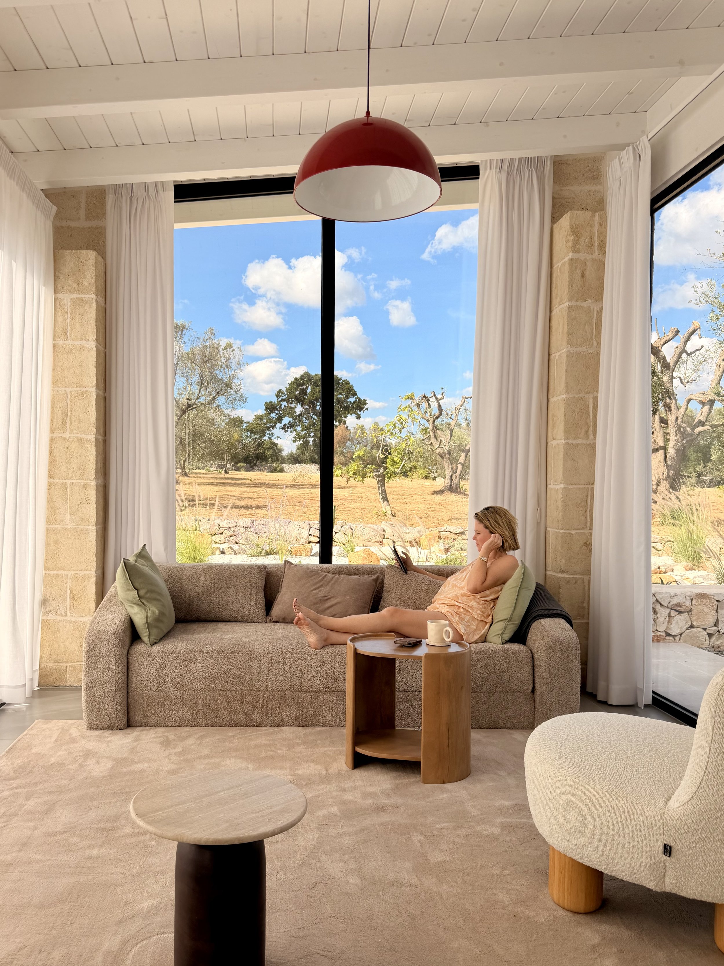 Relaxing on the sofa by floor-to-ceiling windows at Trullo Ostro