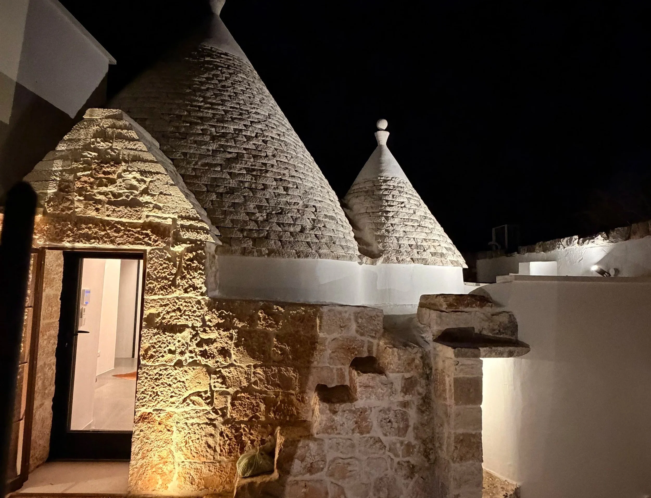 Stone trullo cones lit at night at Trullo Ostro, a Fable Retreats villa near Ostuni