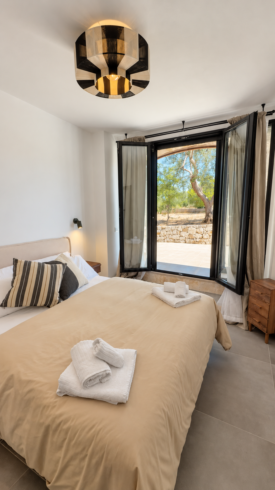 Bedroom with striped pillows and olive grove view at Trullo Ostro
