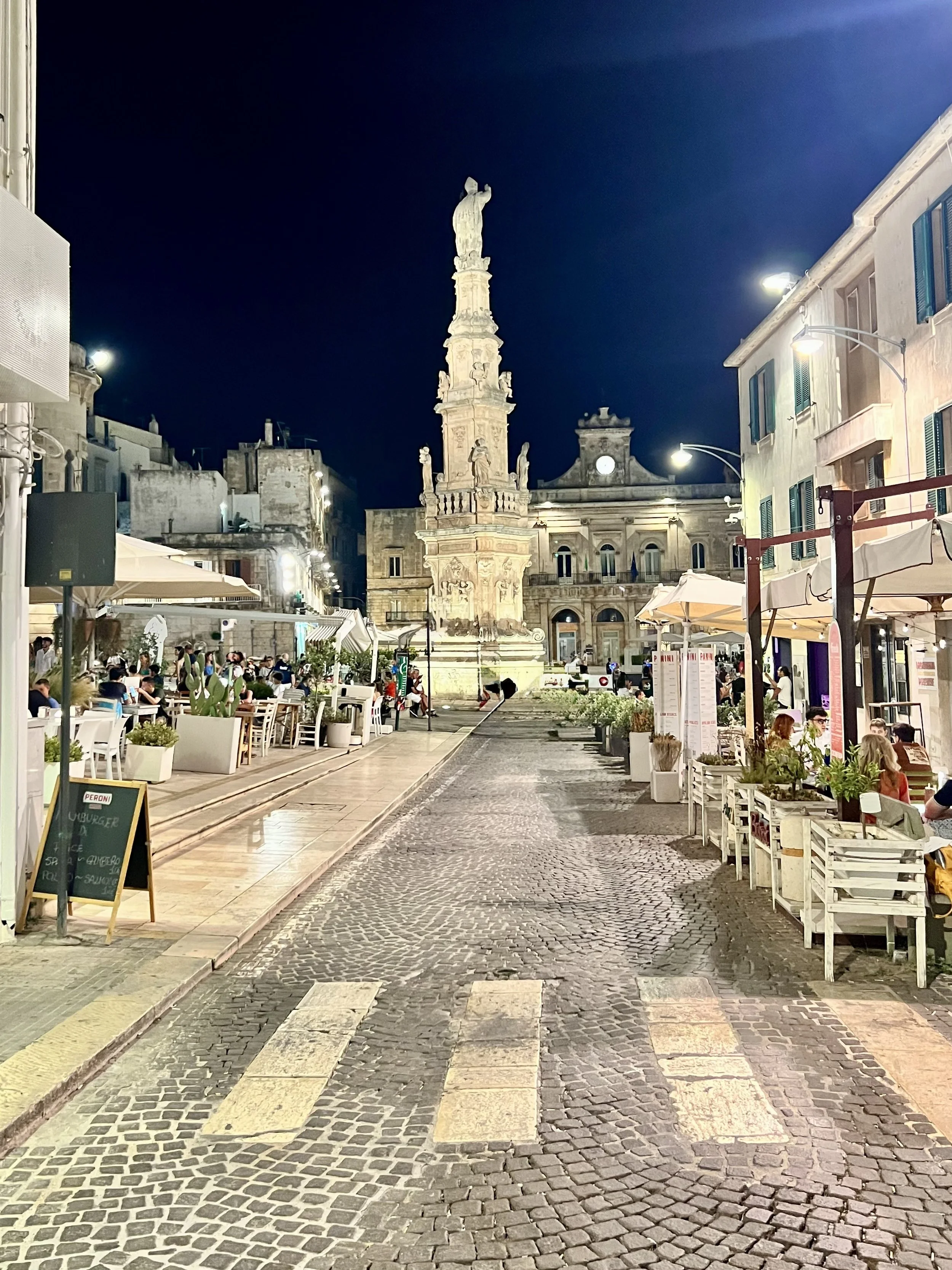 Evening piazza with cafés and a historic church in Puglia