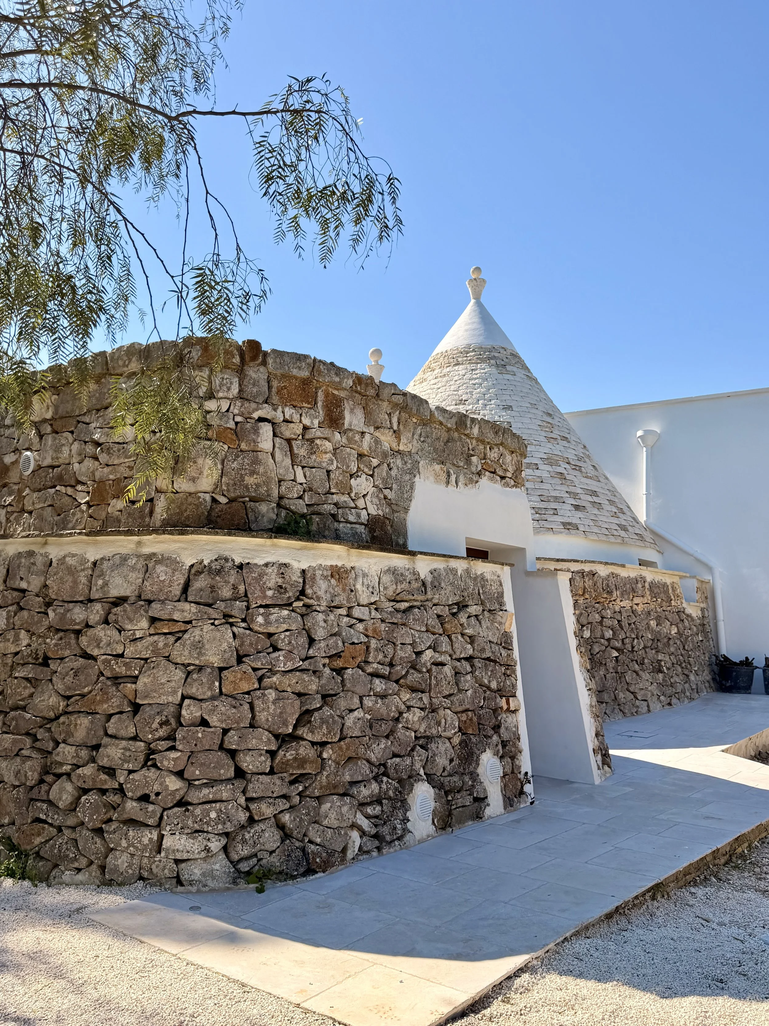 Trullo cone behind dry-stone walls at Trullo Ostro in Puglia