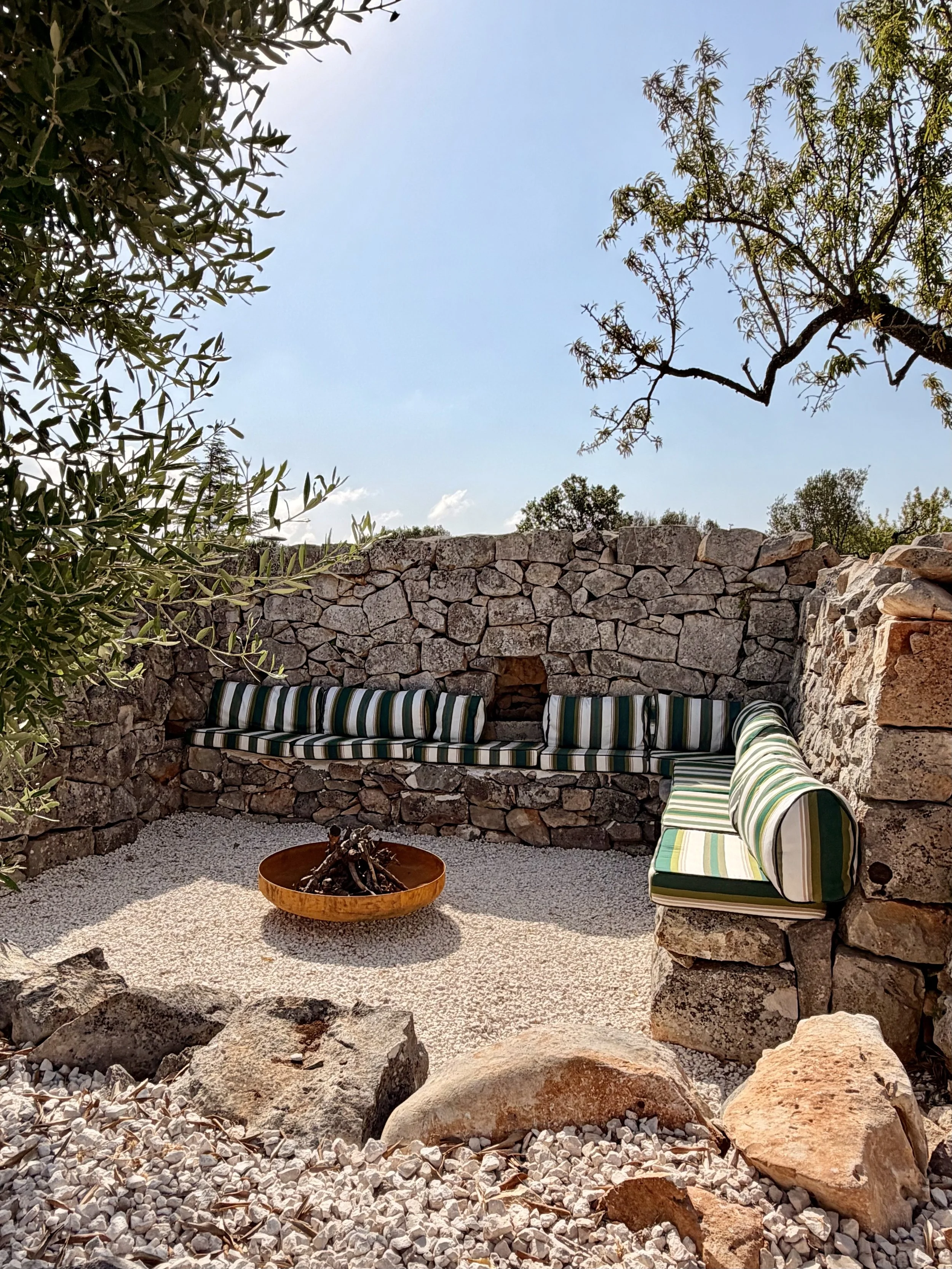 Stone-walled outdoor lounge with striped cushions at Trullo Ostro