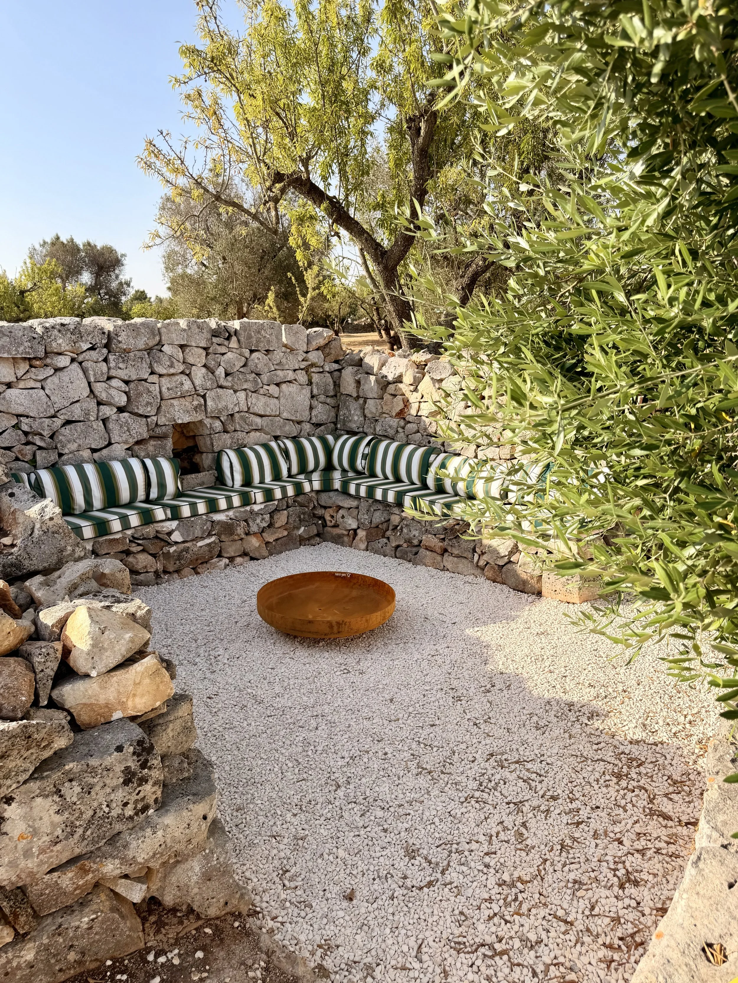 Sunken stone seating area with fire pit at Trullo Ostro, Ostuni