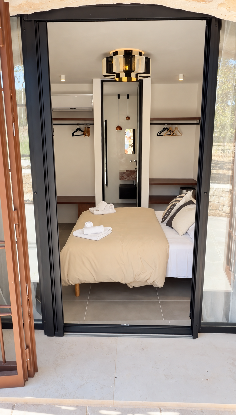 Bedroom with fresh towels and glass doors to the garden at Trullo Ostro