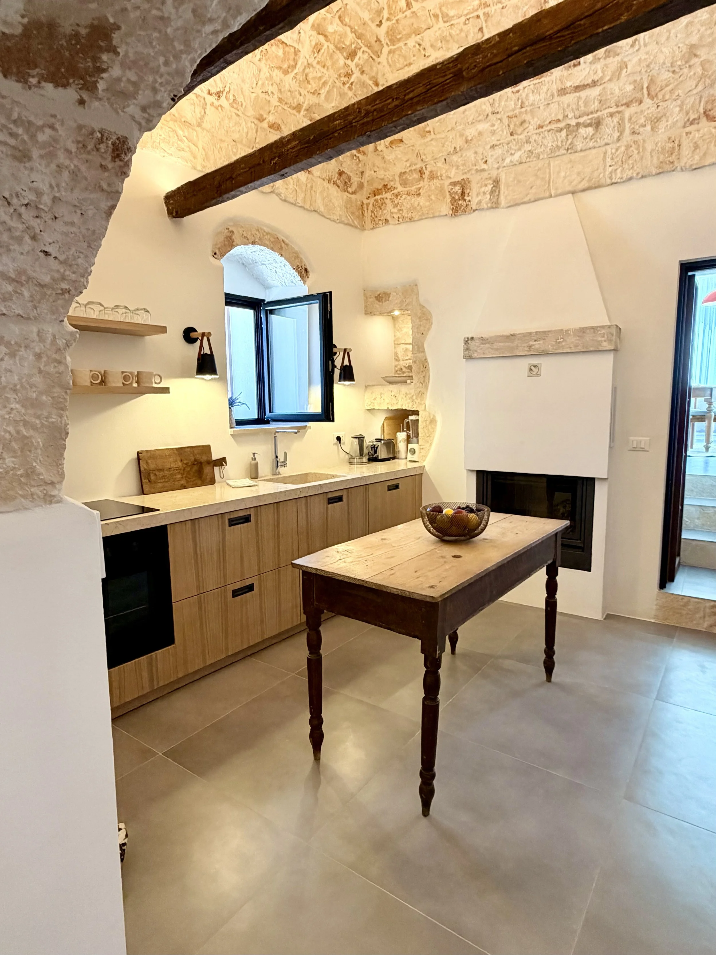 Open kitchen and dining room with fireplace at Trullo Ostro, Ostuni