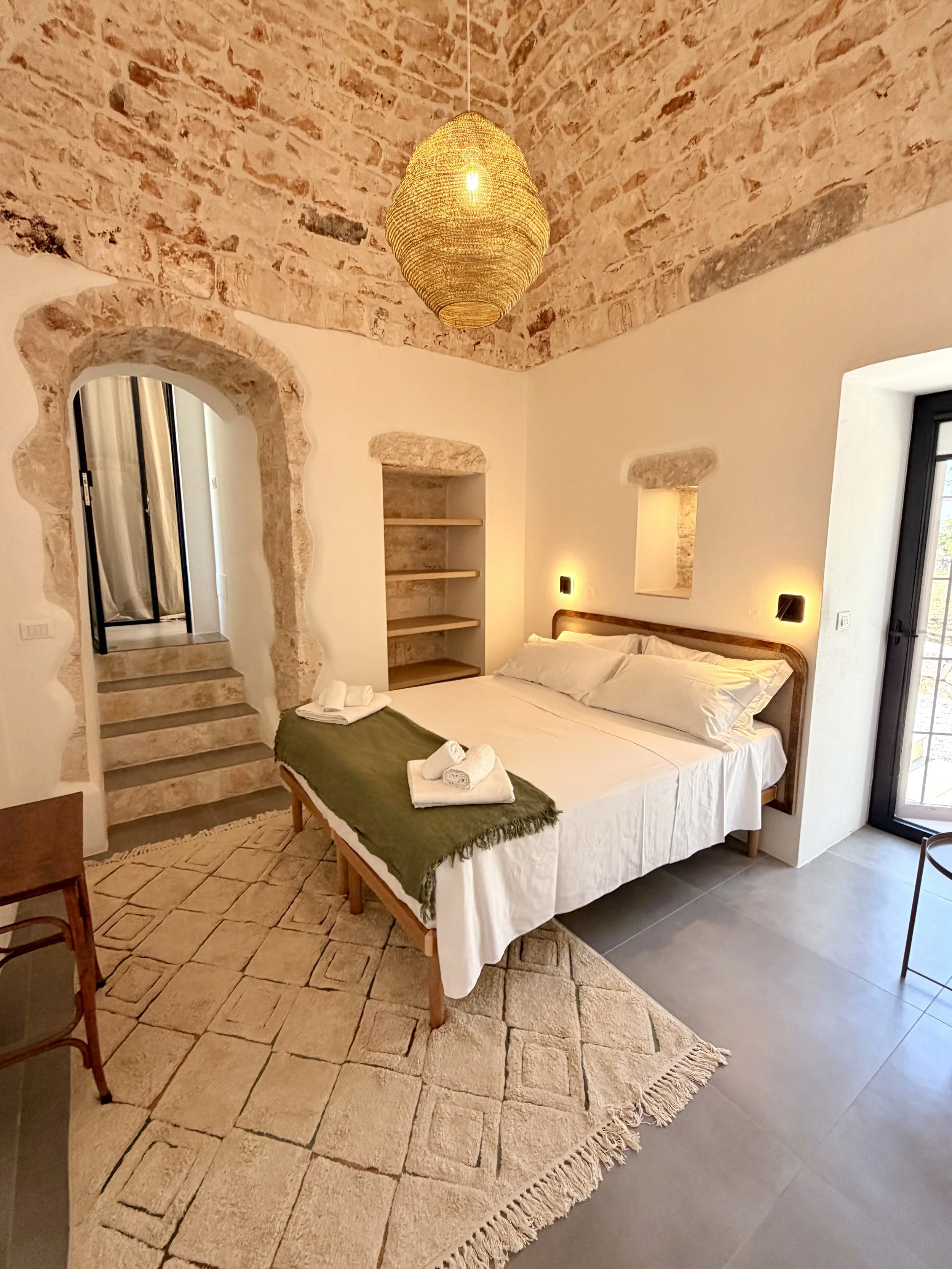 Bedroom with stone arches and steps at Trullo Ostro by Fable Retreats