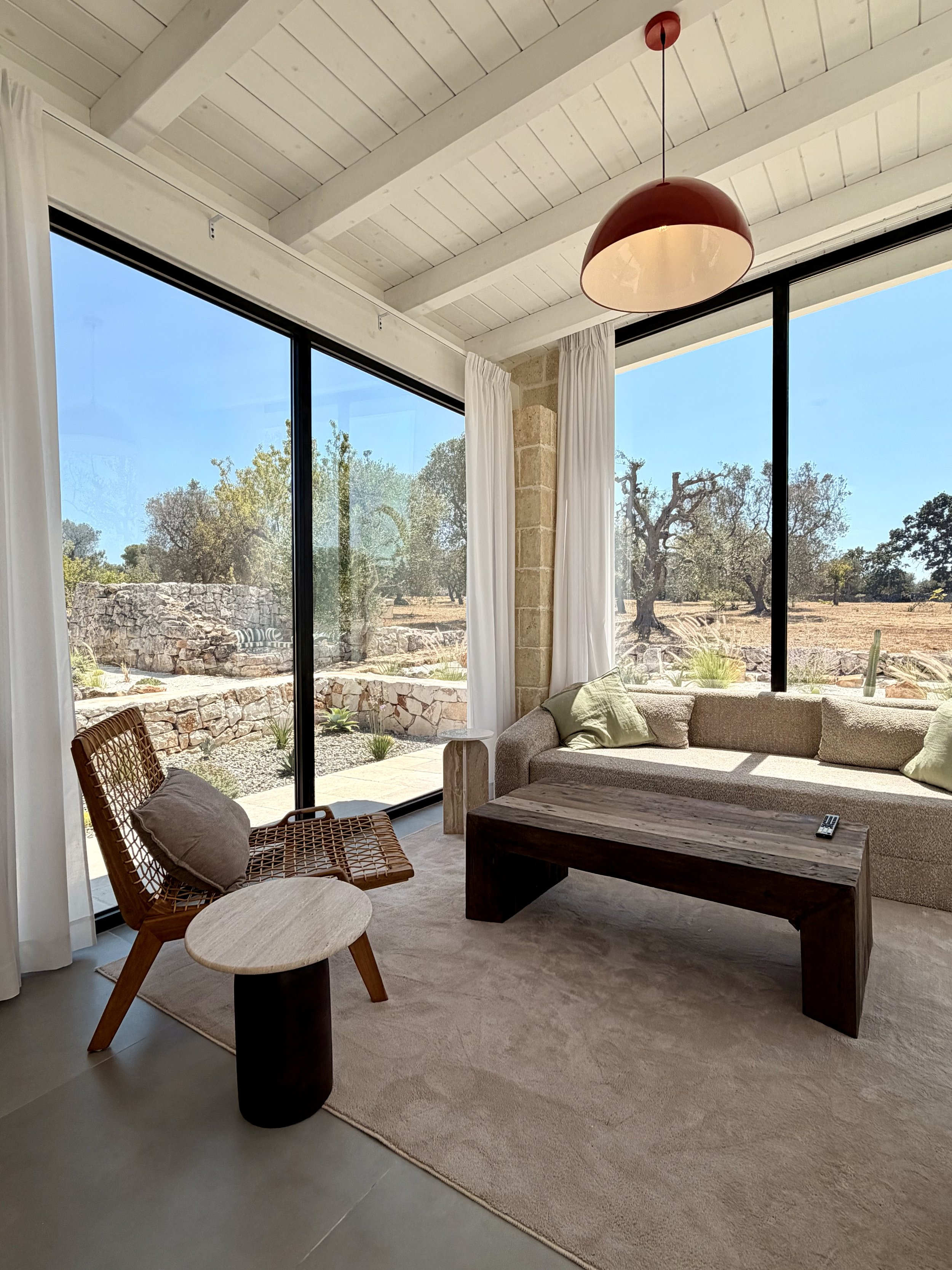 Living room with floor-to-ceiling windows onto the garden at Trullo Ostro