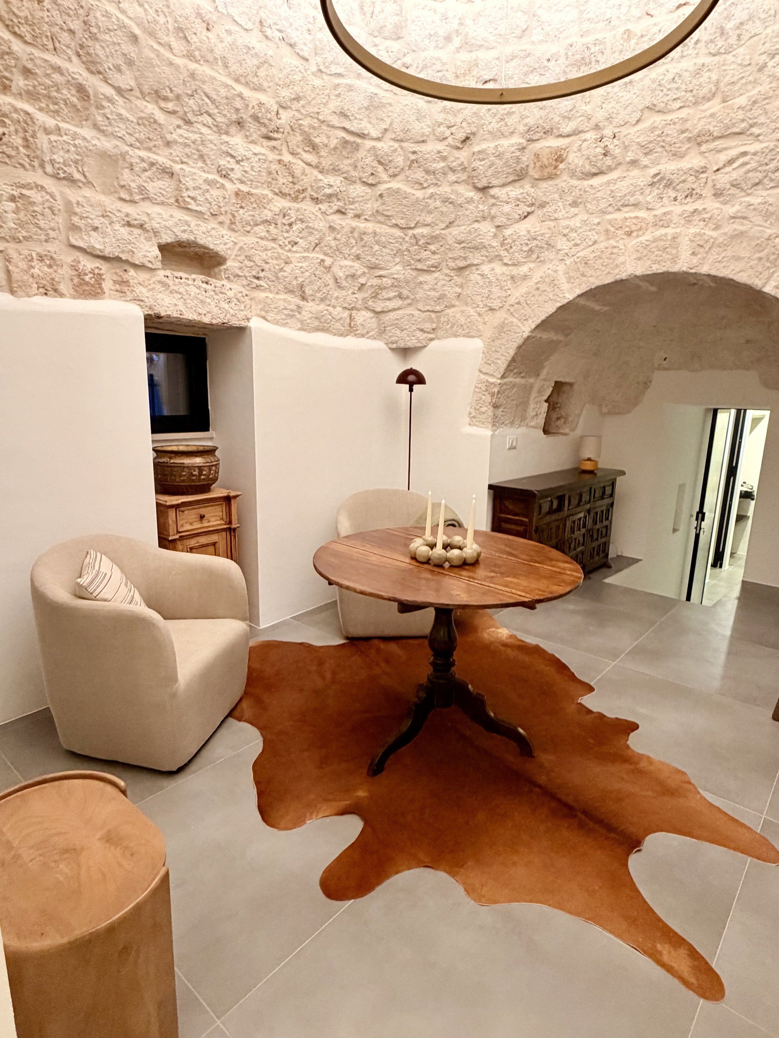 Sitting area with armchairs and stone arch inside the trullo at Trullo Ostro