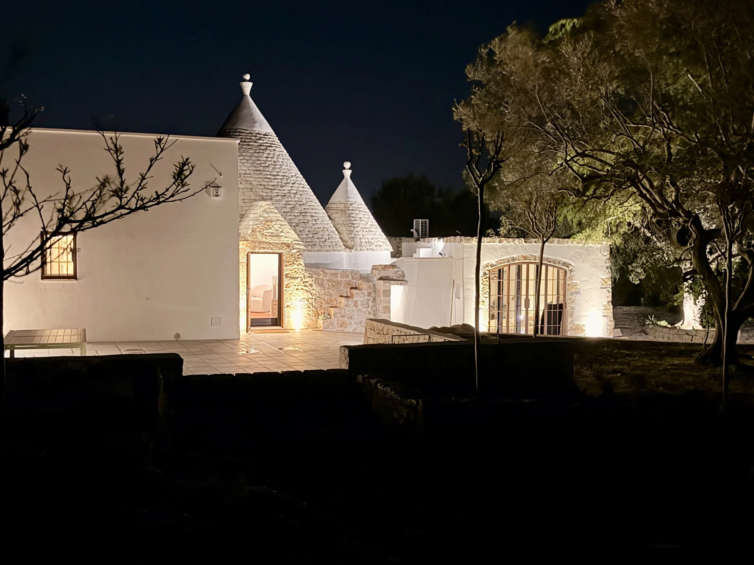 Whitewashed trullo cones lit at night at Trullo Ostro, a Fable Retreats villa near Ostuni, Puglia