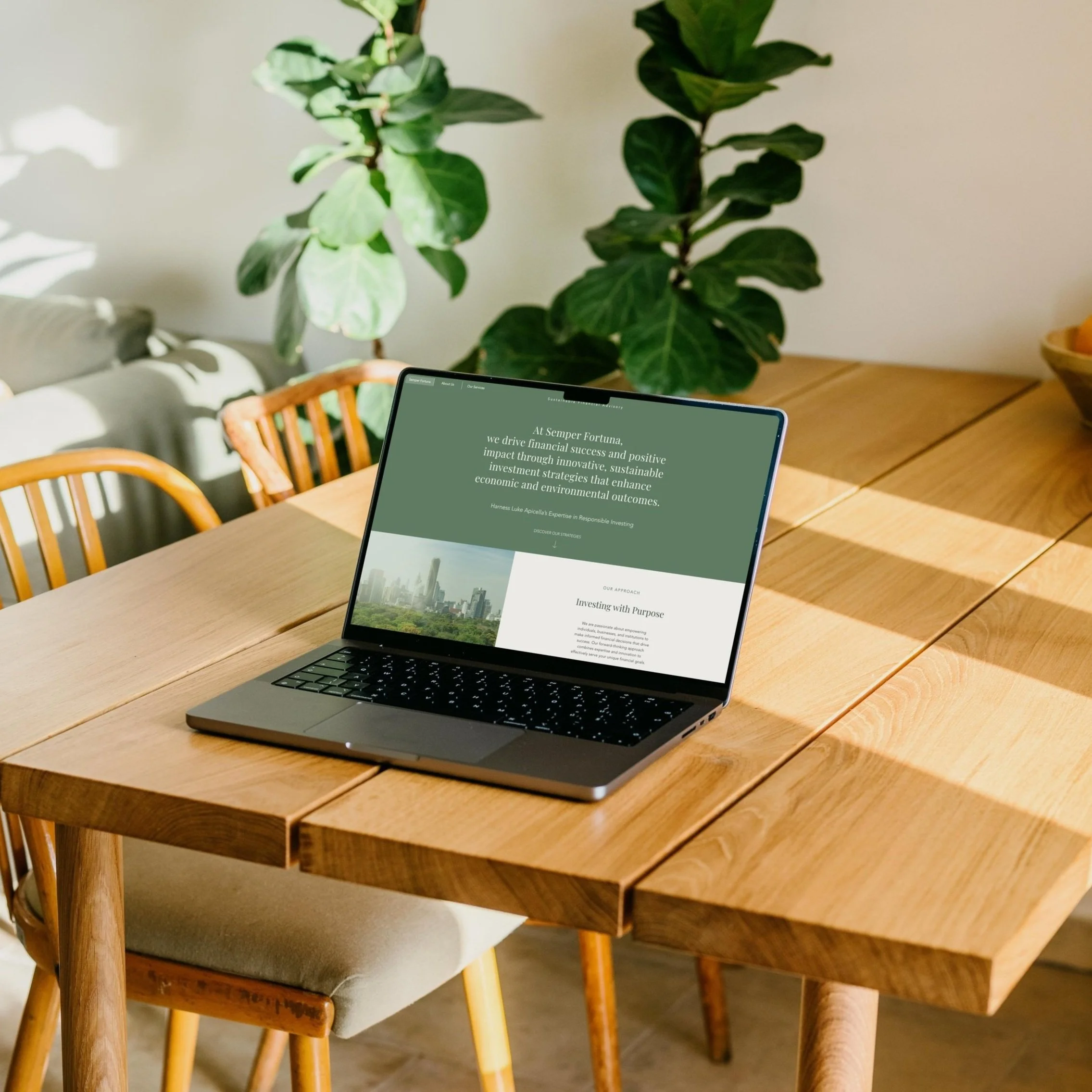 A laptop on a wooden dining table displaying a website related to responsible investing. The table is in a room with sunlight, and large green leafy plants are in the background.