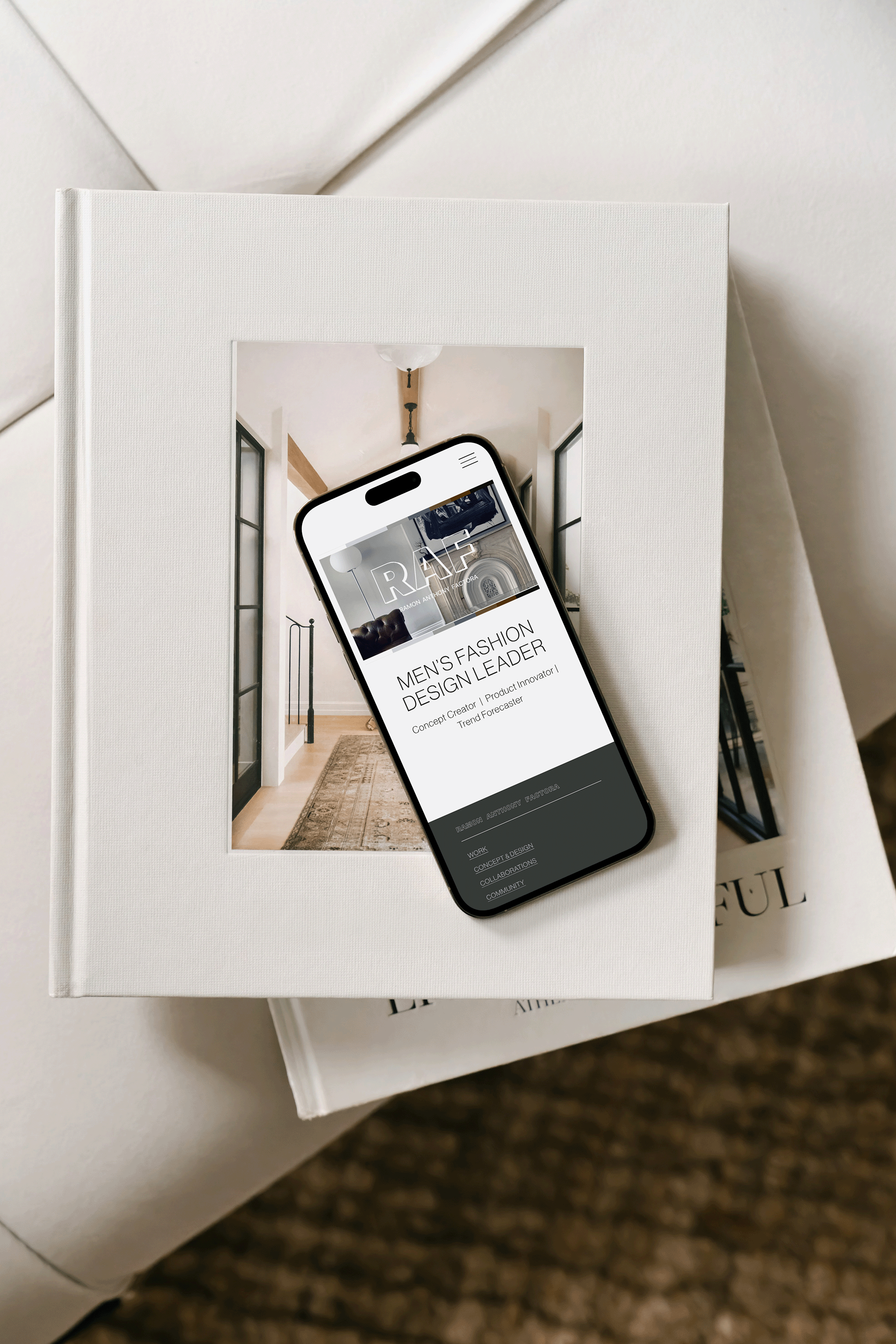 Smartphone displaying a fashion website resting on a white book on a table, with another book underneath.
