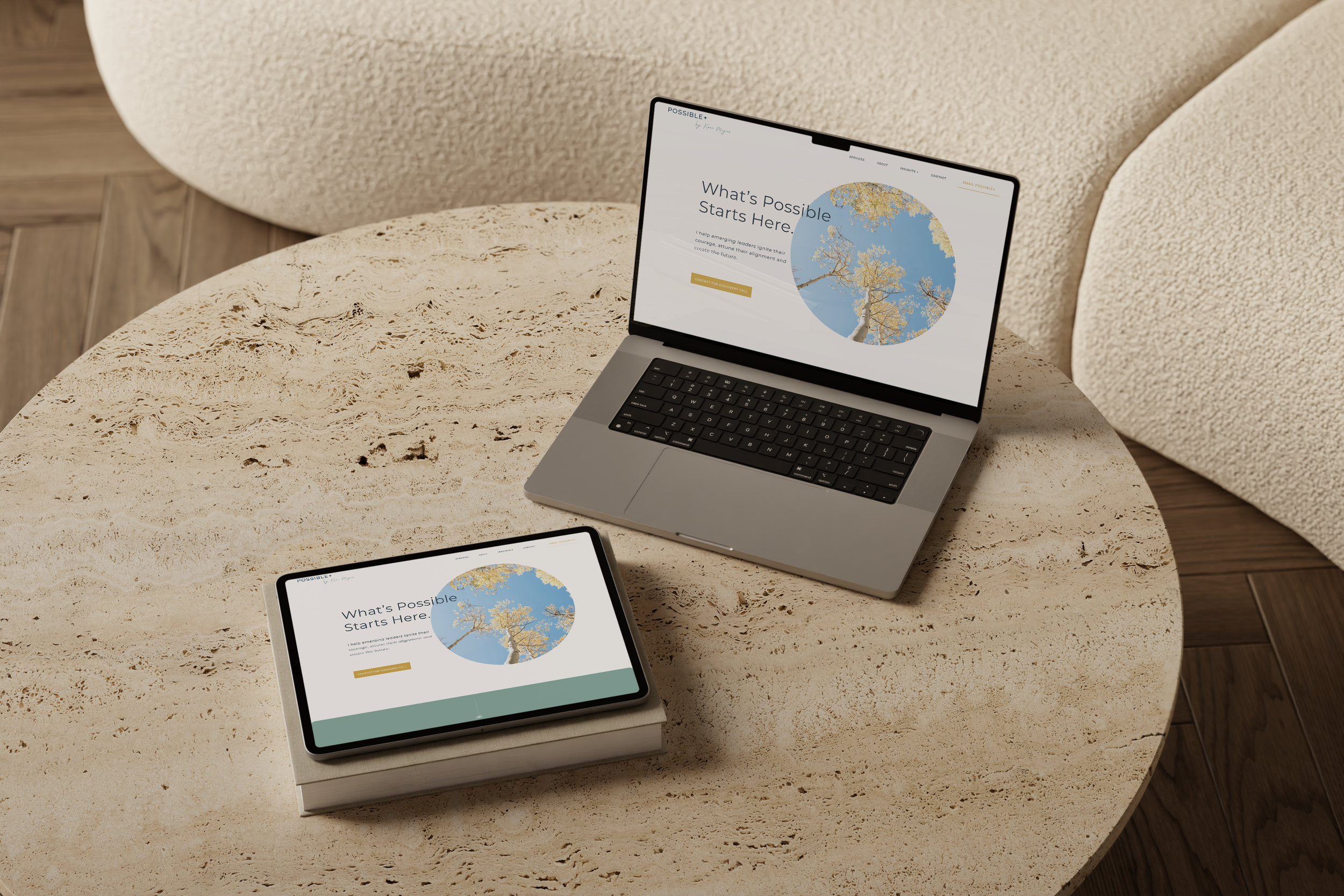 A laptop and a tablet displaying a website titled 'What's Possible Starts Here' on a round beige stone table, with a sofa in the background.