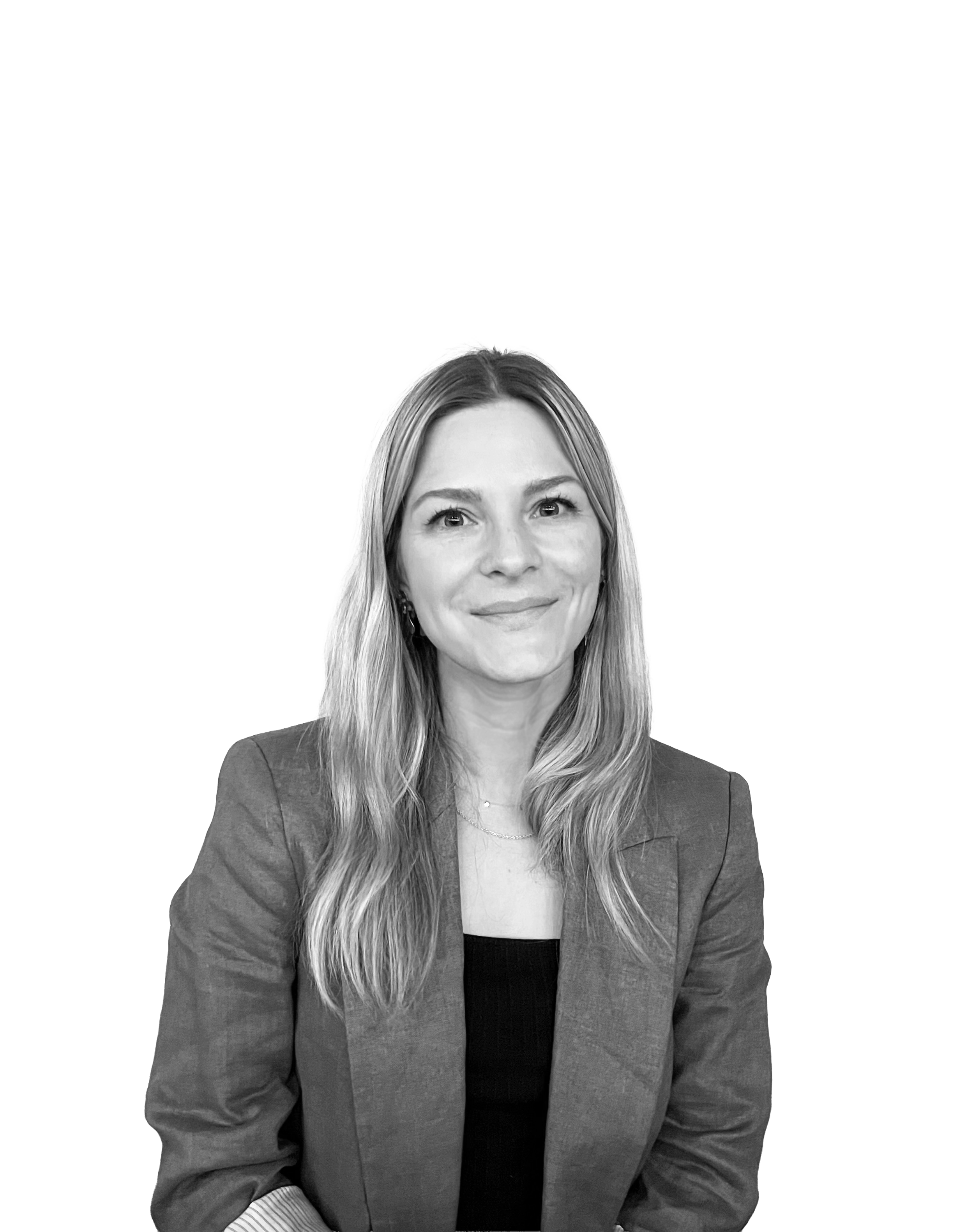 Black and white portrait of a woman with long, wavy hair, wearing a blazer and a black top, smiling softly at the camera, with a partially obscured background.