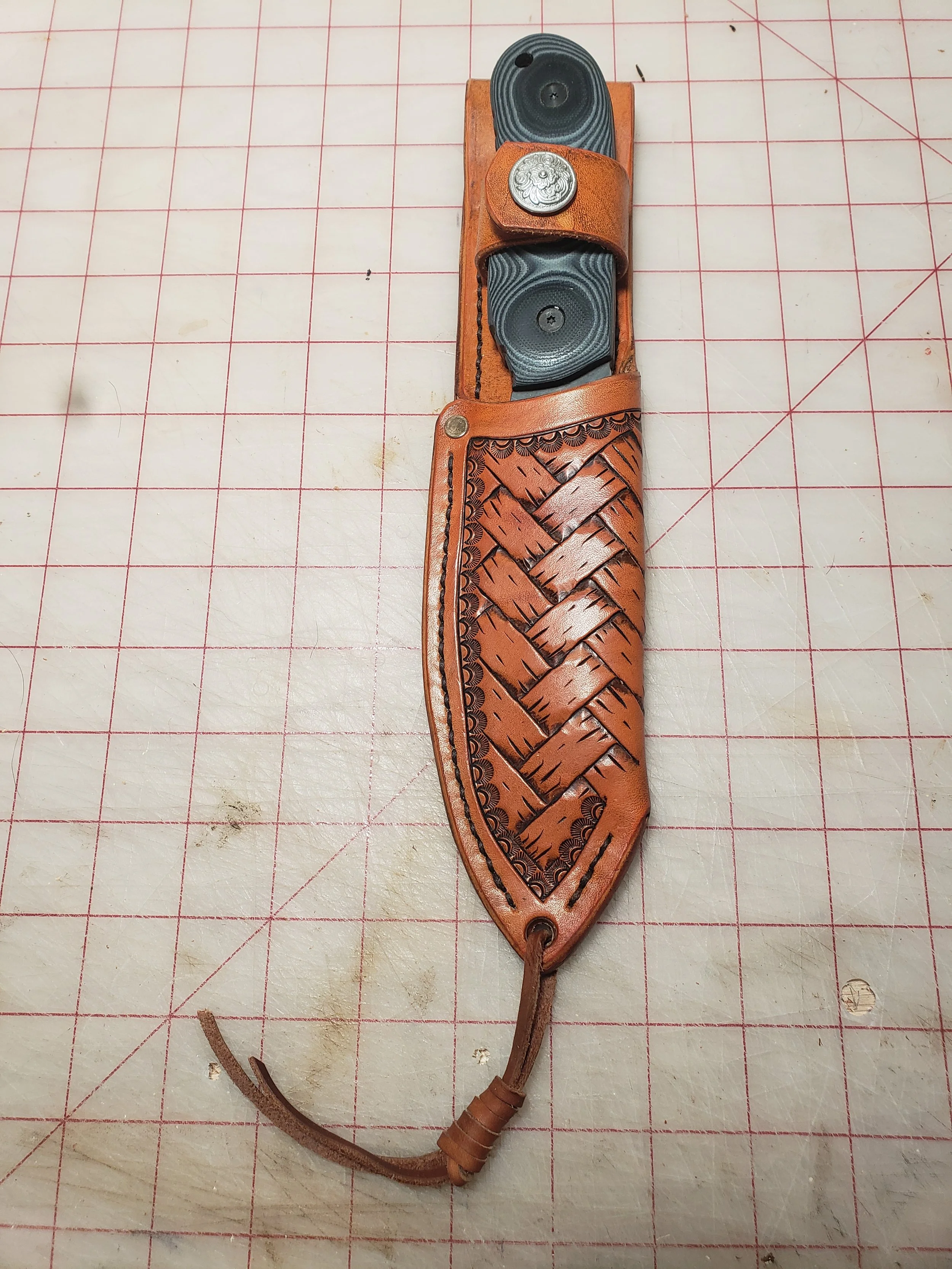 Basket weave design leather knife sheath with a strap and leather lanyard.