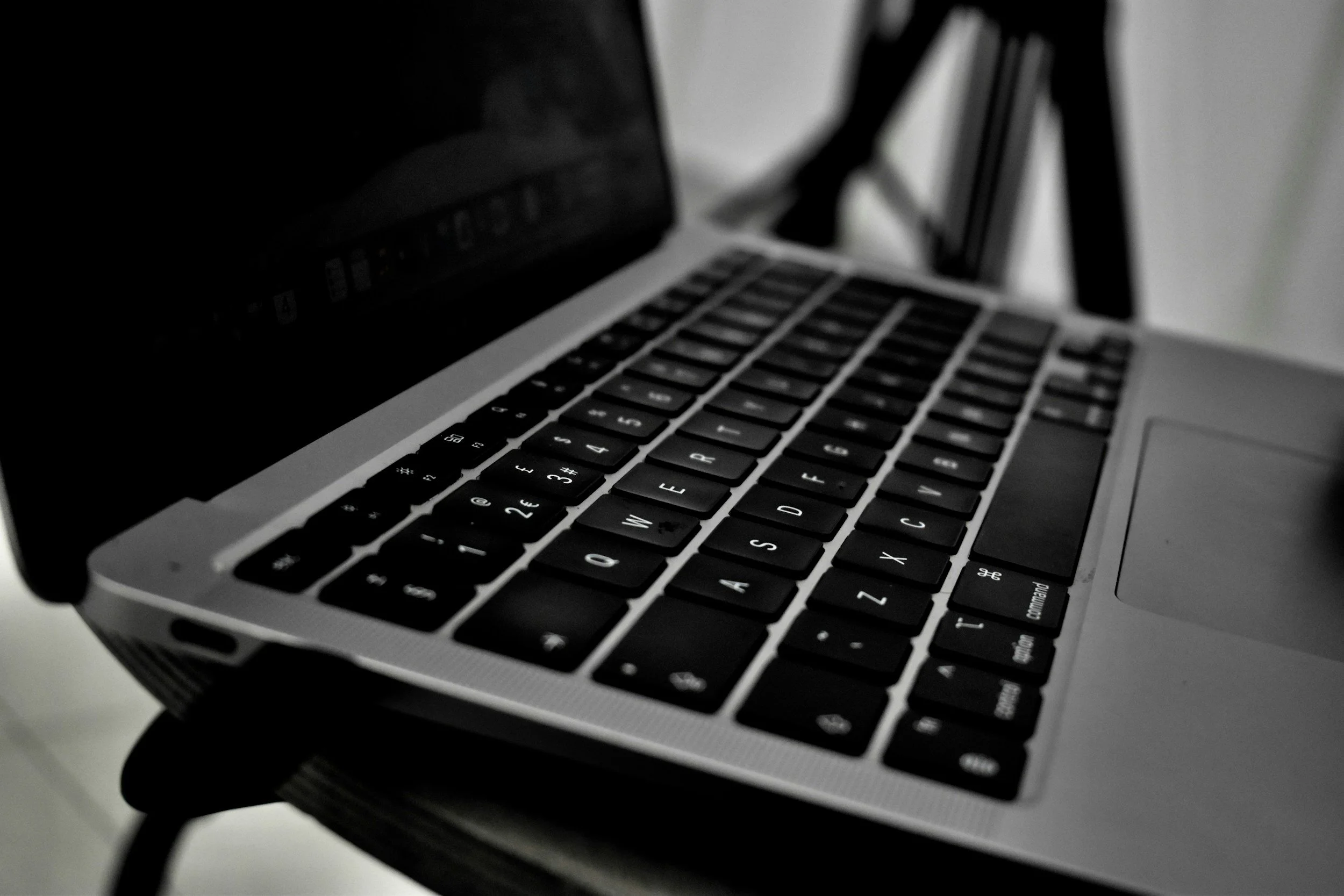 Close-up of a laptop keyboard with black keys and silver body, viewed from an angle.
