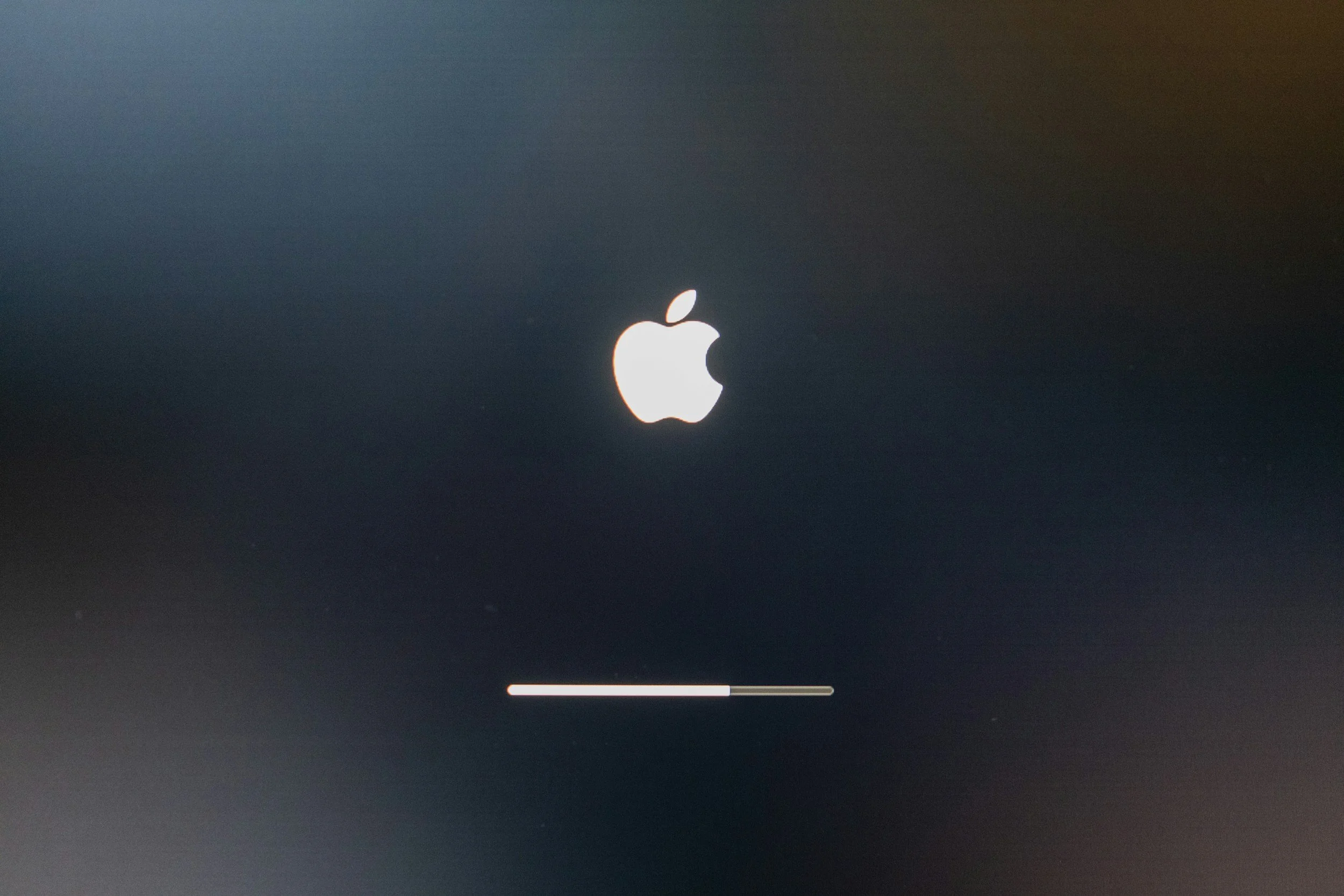 Apple logo with a progress bar below, indicating a software update in progress.