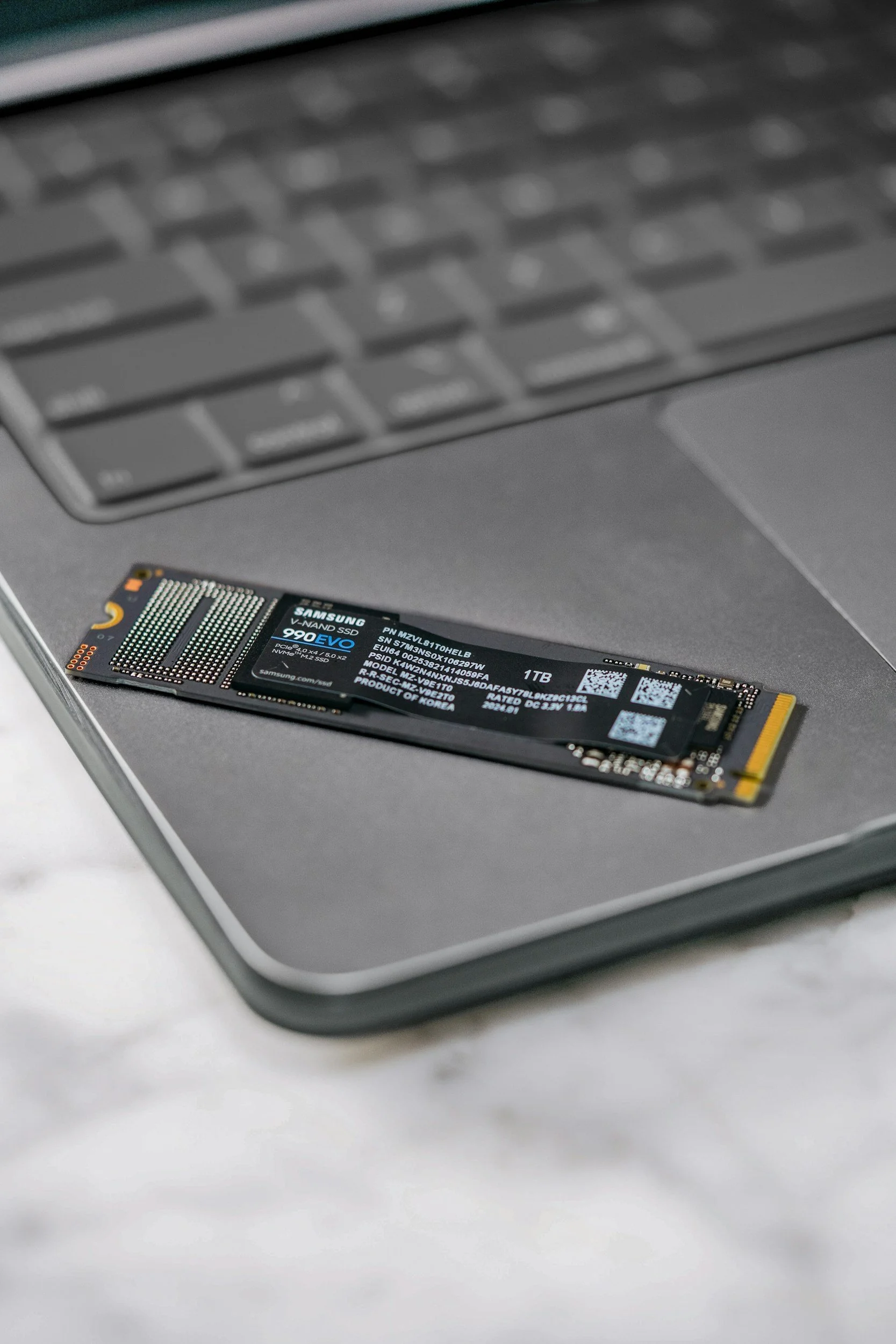A Samsung 1TB NVMe solid-state drive (SSD) on a laptop keyboard.