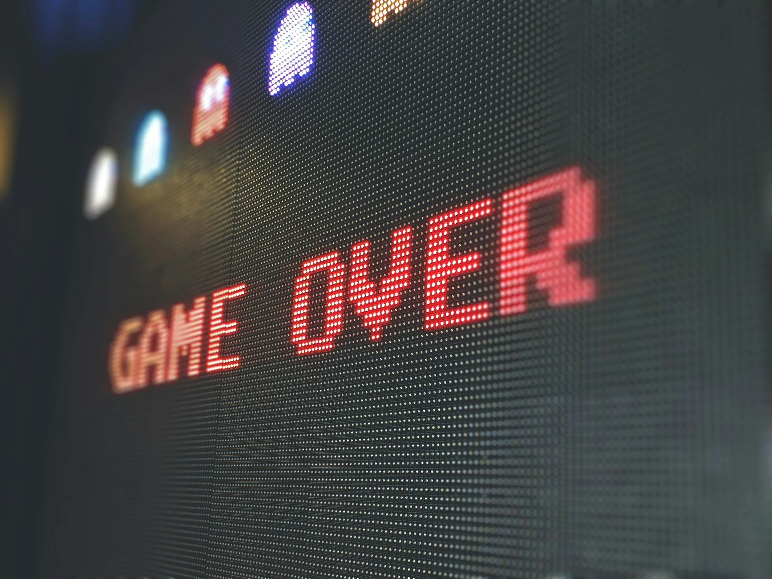 Close-up of a digital LED display with a red message reading 'GAME OVER' and icons above it in various colors.