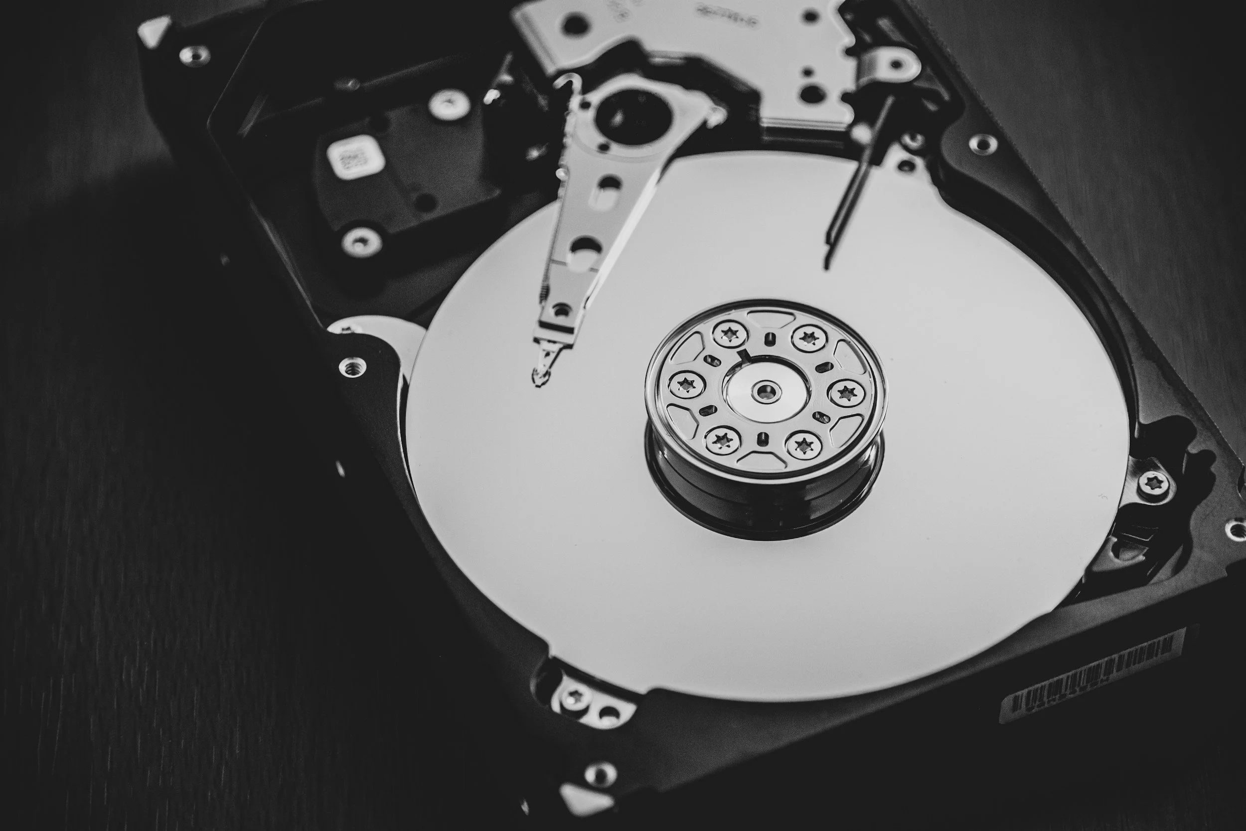 Black and white photo of an opened hard disk drive showing the disk platter and read/write arm.