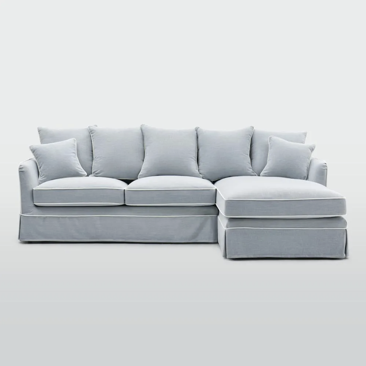 A relaxed yet refined chaise sofa designed for modern living, featuring a tailored slipcover with elegant piping and a generous right-hand chaise for added comfort. It offers lasting support and a soft, inviting feel, while a range of fabric options 