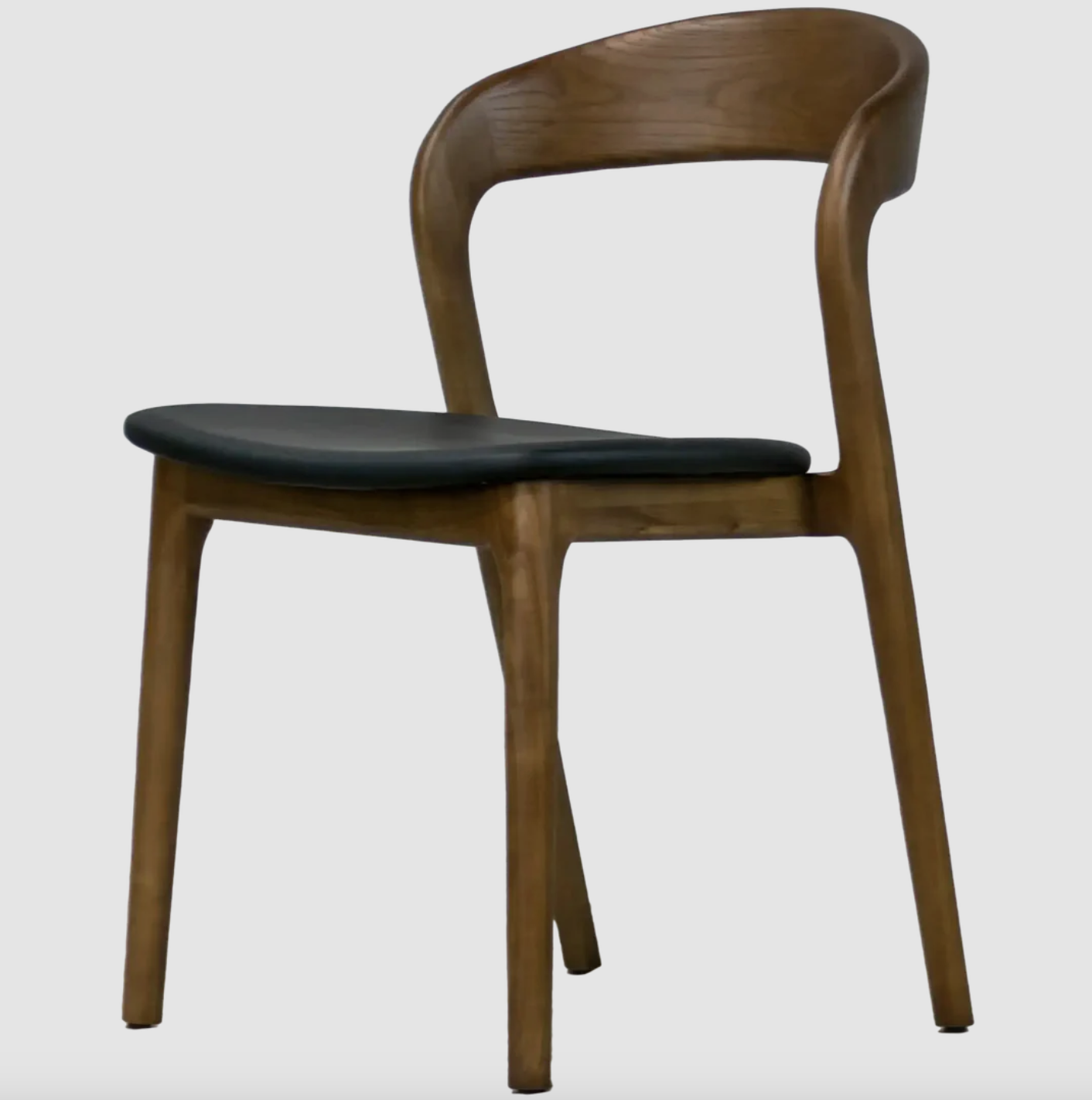 A sleek armless chair crafted from solid walnut, featuring a gently curved backrest and a cushioned seat for added comfort. Its clean, organic lines bring a warm, modern touch to any space.
