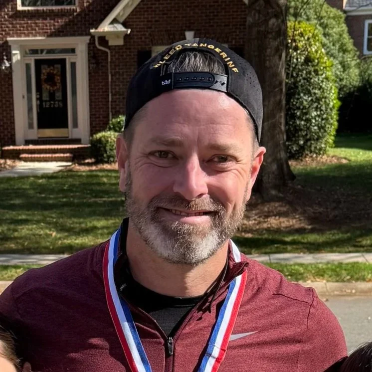 Mavericks football club logo with black, white, and orange design elements, a rose at the center, and three stars above.