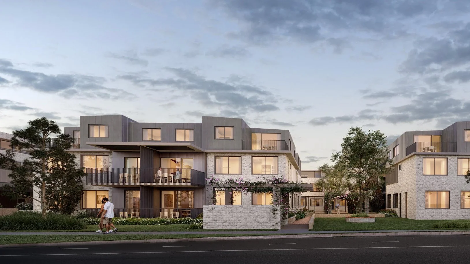 Modern multi-story residential building with large windows, balconies, and surrounding greenery during dusk.