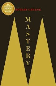 Book cover titled 'Mastery' by Robert Greene, featuring large gold feather-like shapes on a dark background.