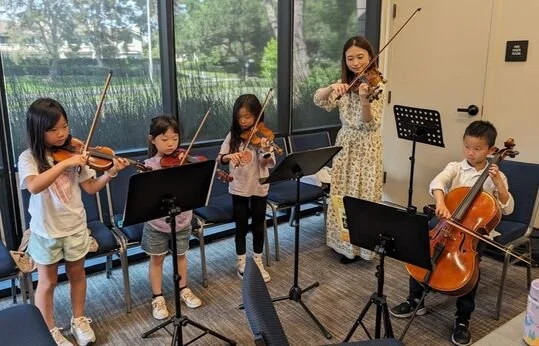 Eriko Tsuji guiding young violin students in an ensemble rehearsal