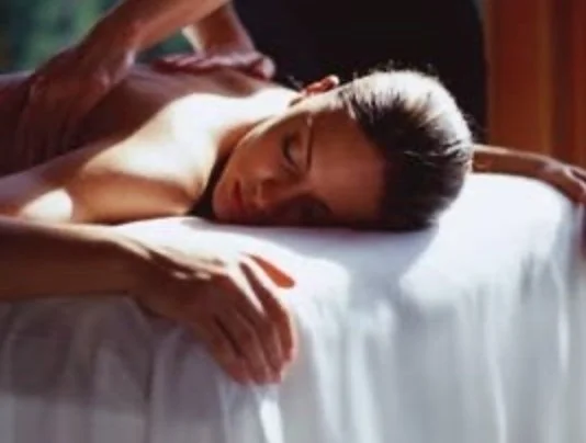 Person lying face down on a bed with a white sheet, resting his head on the mattress.