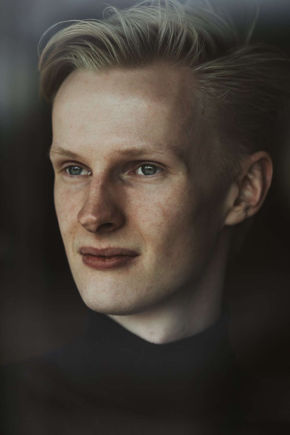 Nahaufnahme eines jungen, blonden Mannes mit blauen Augen