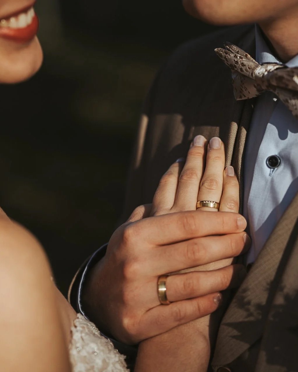Ein Damen- und ein Herrenhandschlag auf einer Hochzeitsfeier, die Hände tragen Eheringe. Es sind Details einer Handhaltung bei einer emotionalen Situation zu sehen.
