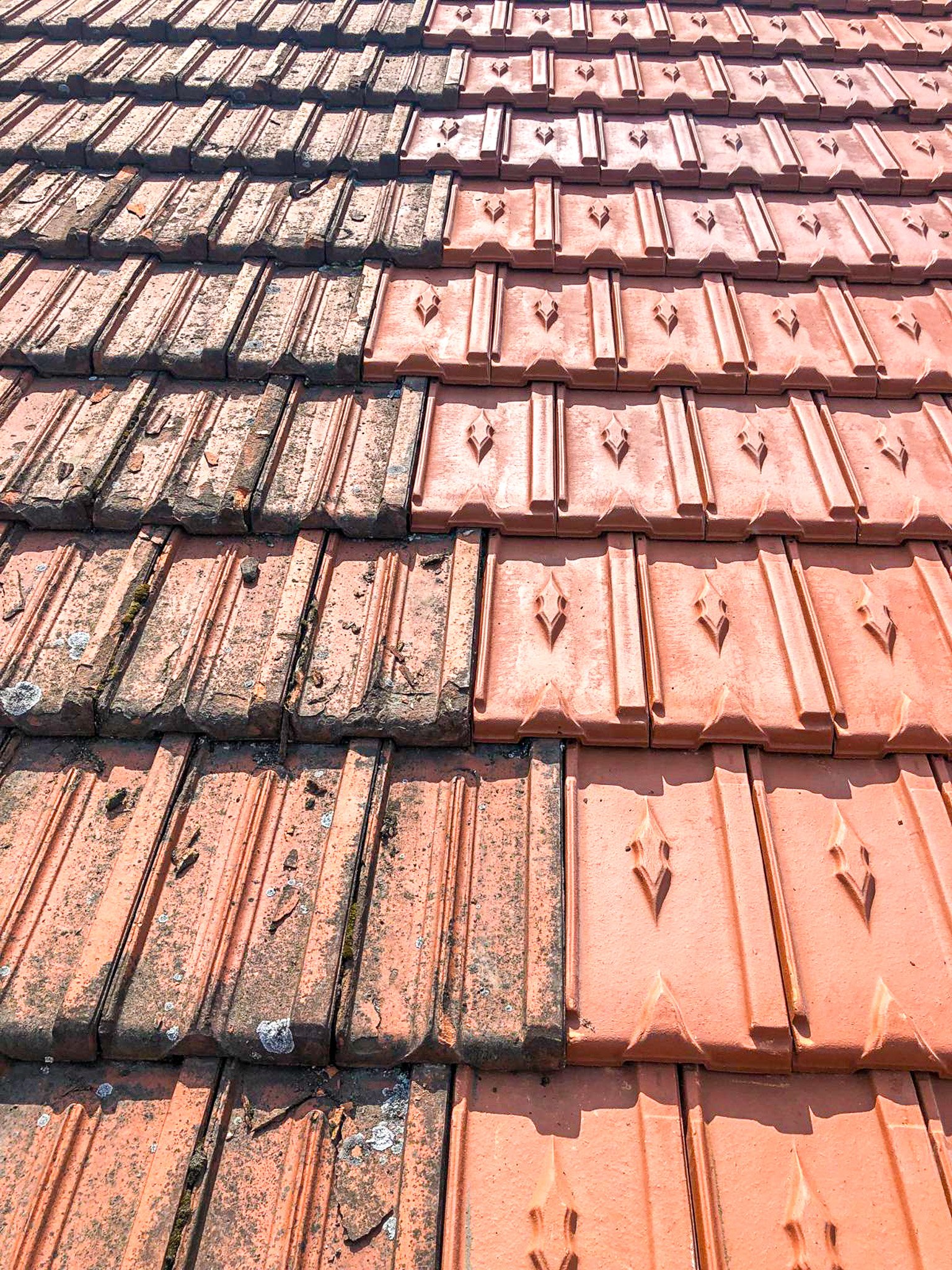 Une toiture avec moitié de tuiles anciennes tachées et moitié de tuiles neuves et propre