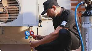 Technician checking HVAC system gauges and equipment outside.