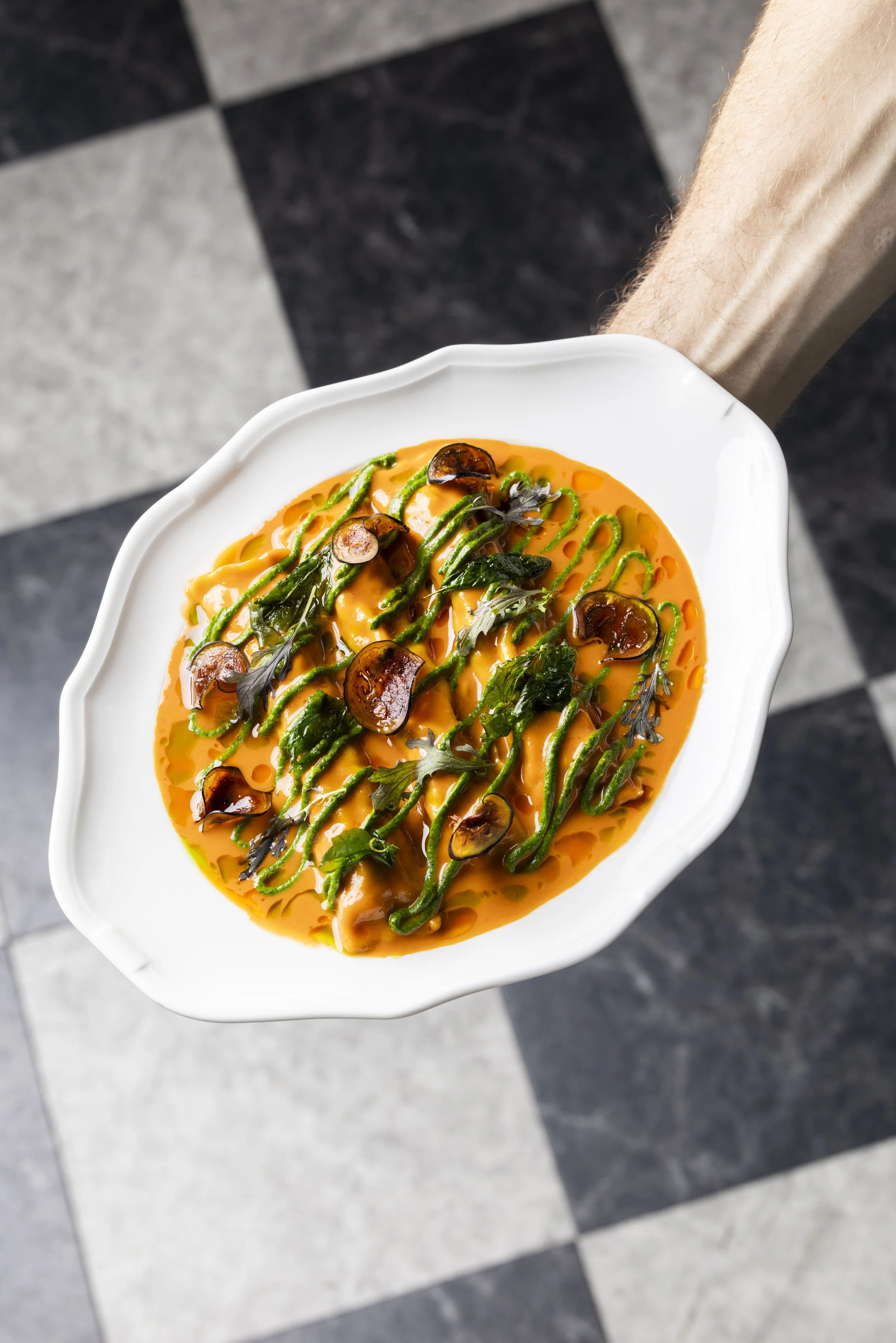 Plat de pâtes aux champignons, épinards, sauce orange, décor de pesto