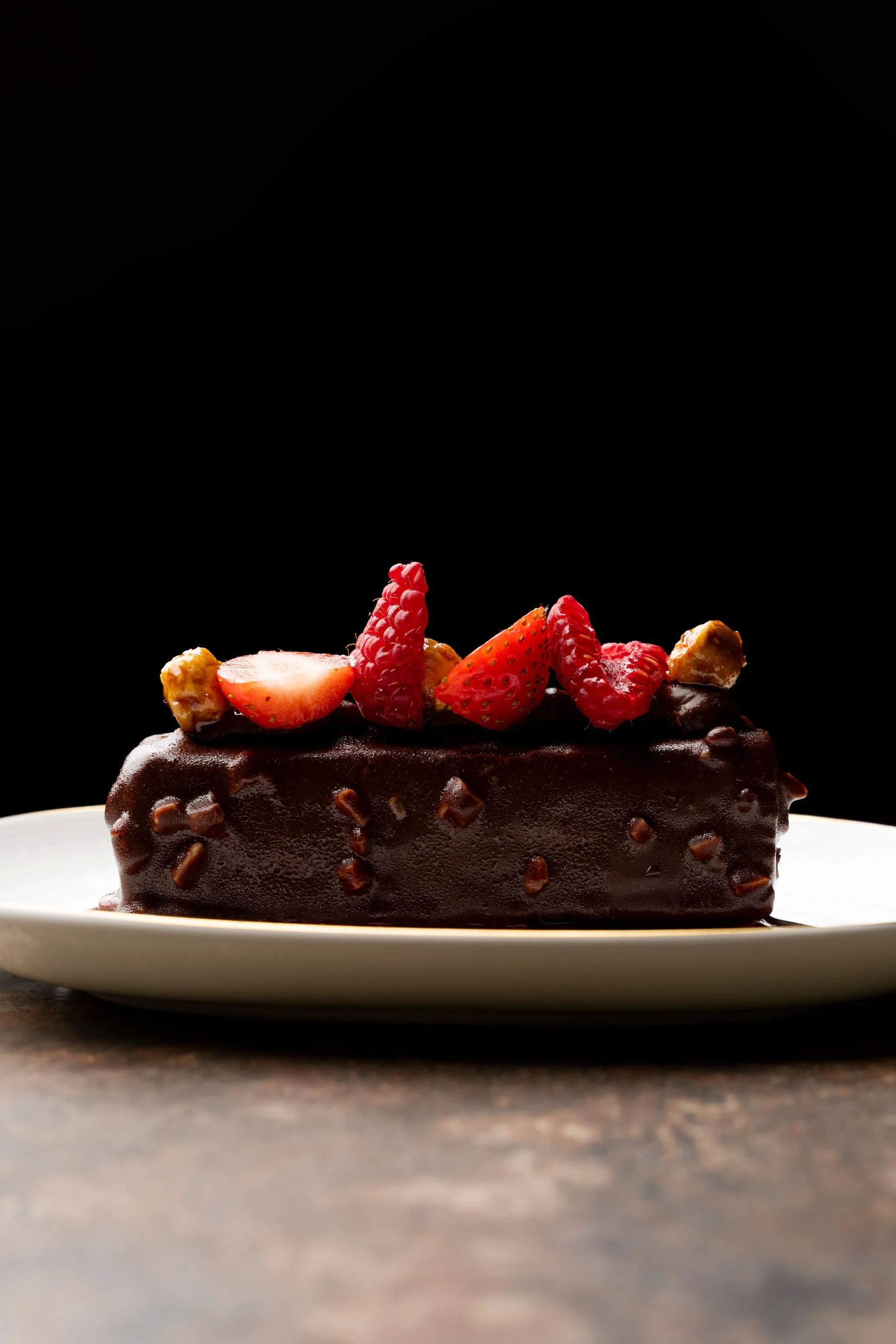 Gâteau au chocolat décoré de fraises et de framboises sur une assiette blanche