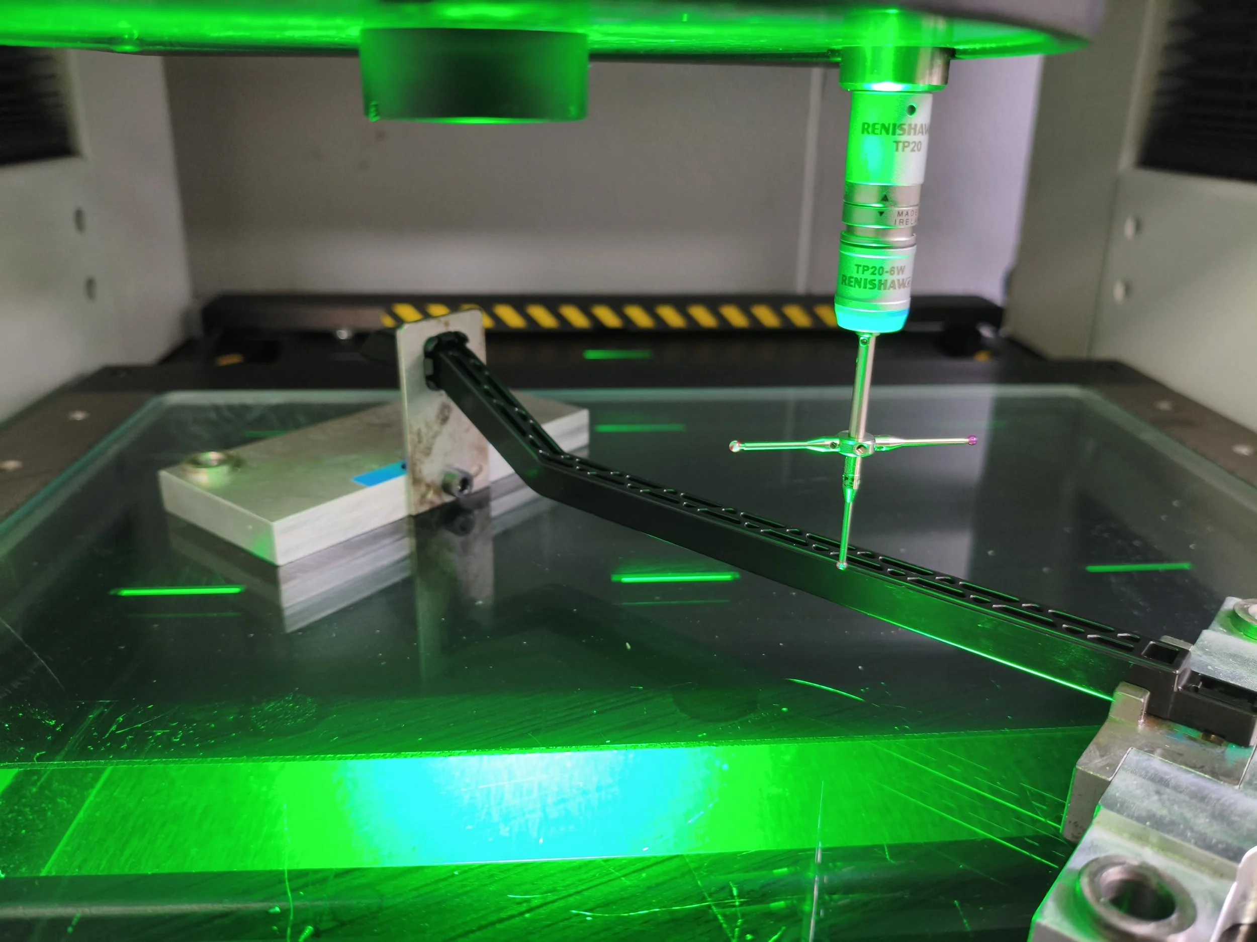 A modern, wooden building with large glass windows is set against a mountain landscape with dry grassy terrain in the foreground and mountains in the background.