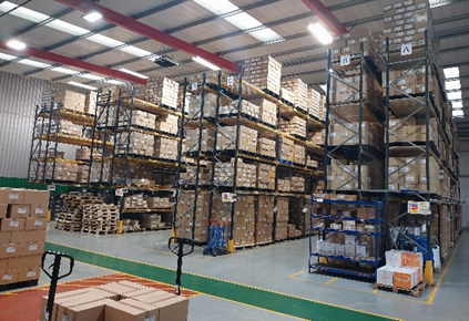 Warehouse with tall metal shelving filled with stacked boxes and pallets.