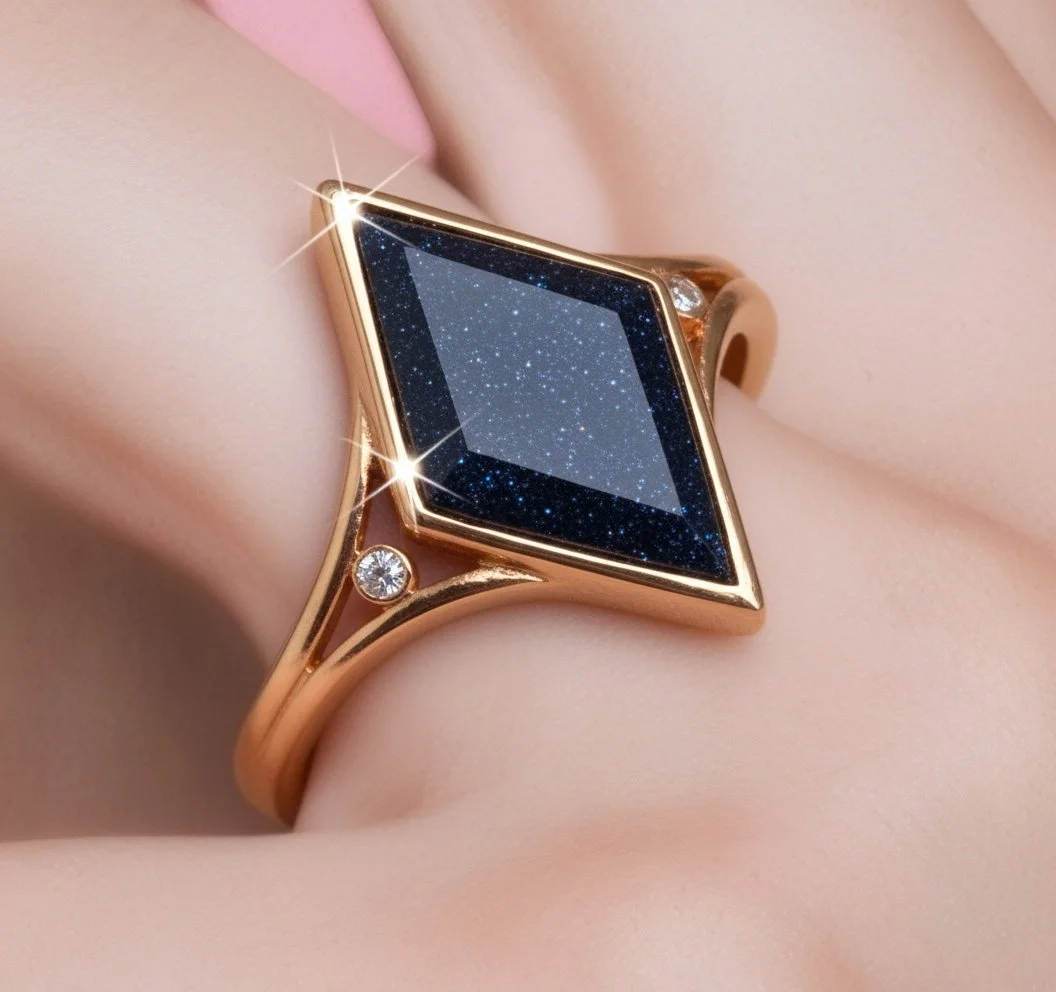 A gold ring with a square-shaped, starry night sky gemstone and a small diamond on the band. The ring is worn on a finger with smooth, fair skin.