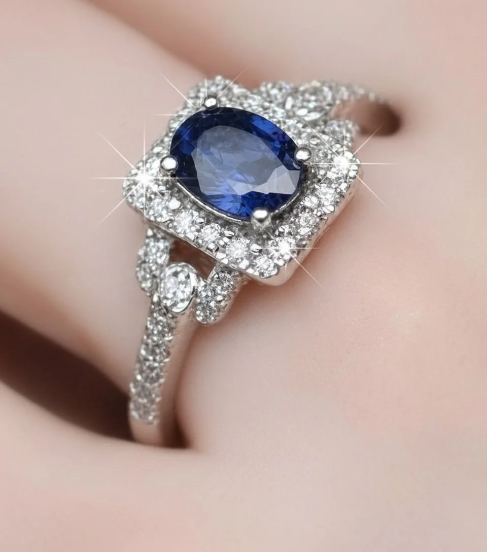 A close-up of a jewelry ring featuring a large oval-cut blue gemstone surrounded by smaller clear diamonds set in a silver band.