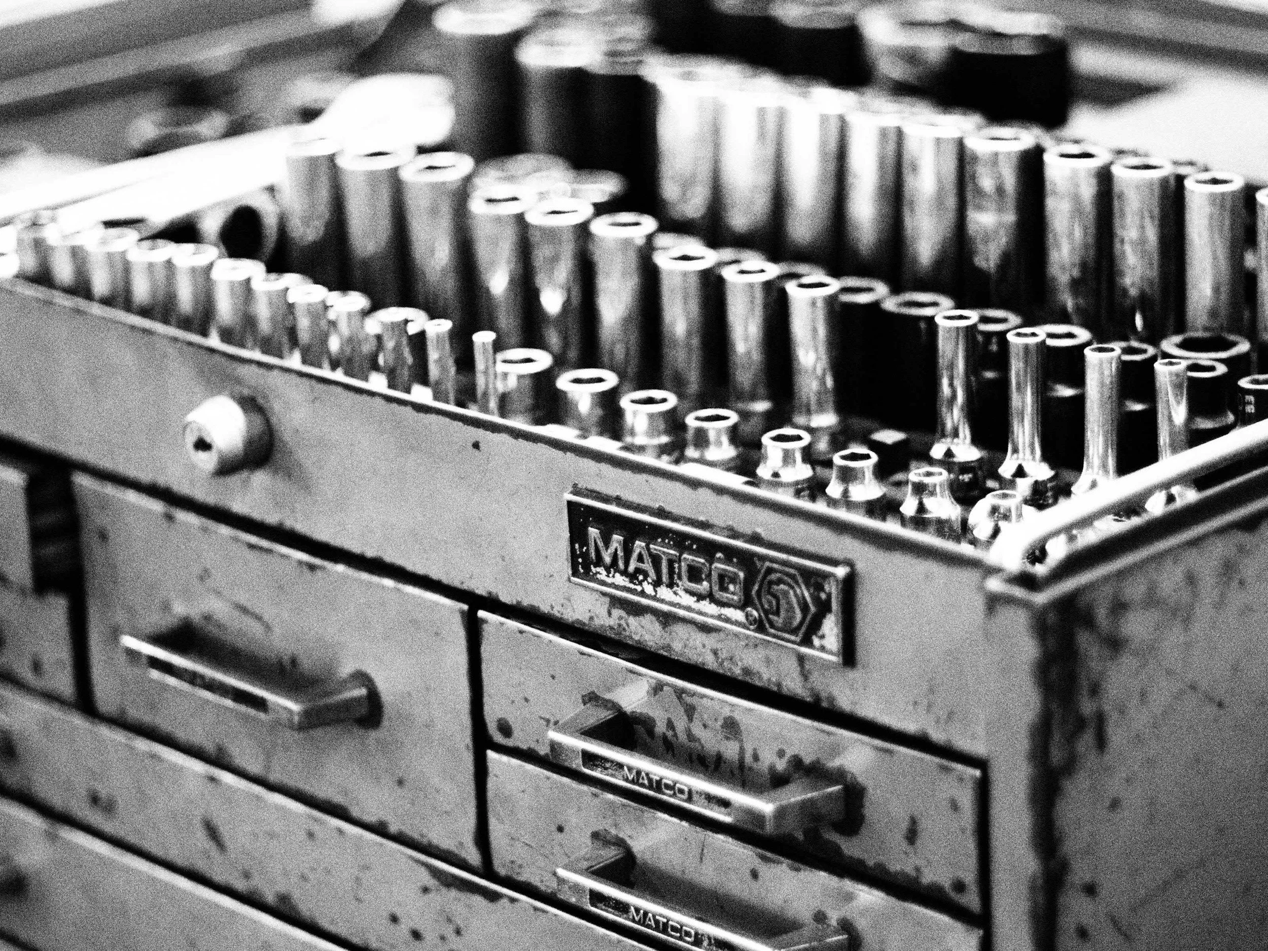 Black and white photo of a vintage tool chest with drawers, showing a variety of metal socket wrenches and tools.