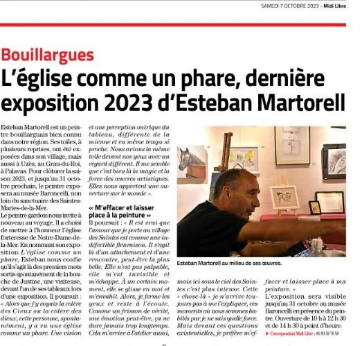 Un homme, Esteban Martorell, parlant dans une galerie d'art avec des œuvres en arrière-plan, lors d'une exposition aux Saintes Maries de la Mer  en 2023.