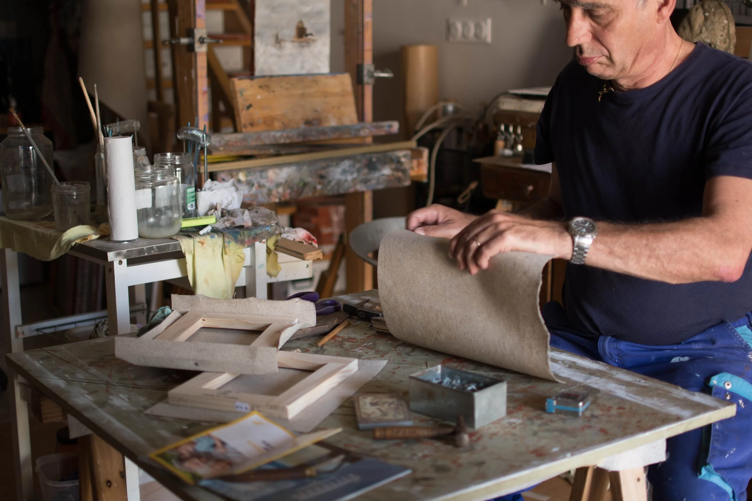 Esteban Martorell travaillant dans son atelier, posant  la toile de lin - encollée à la colle de peau de lapin sur les chässis en bois.