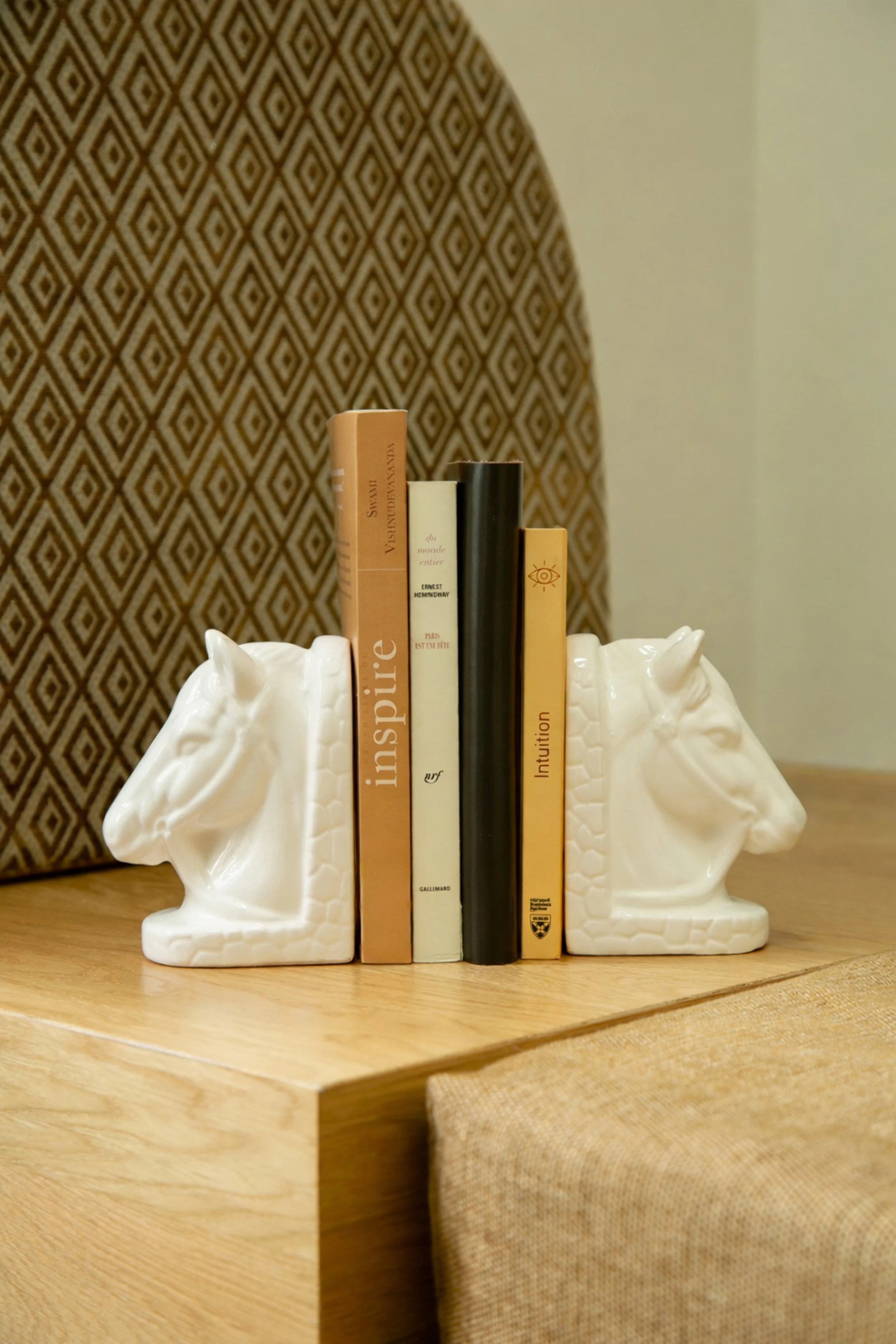 Livrets de livres reposant entre deux têtes de cheval en céramique sur une surface en bois.