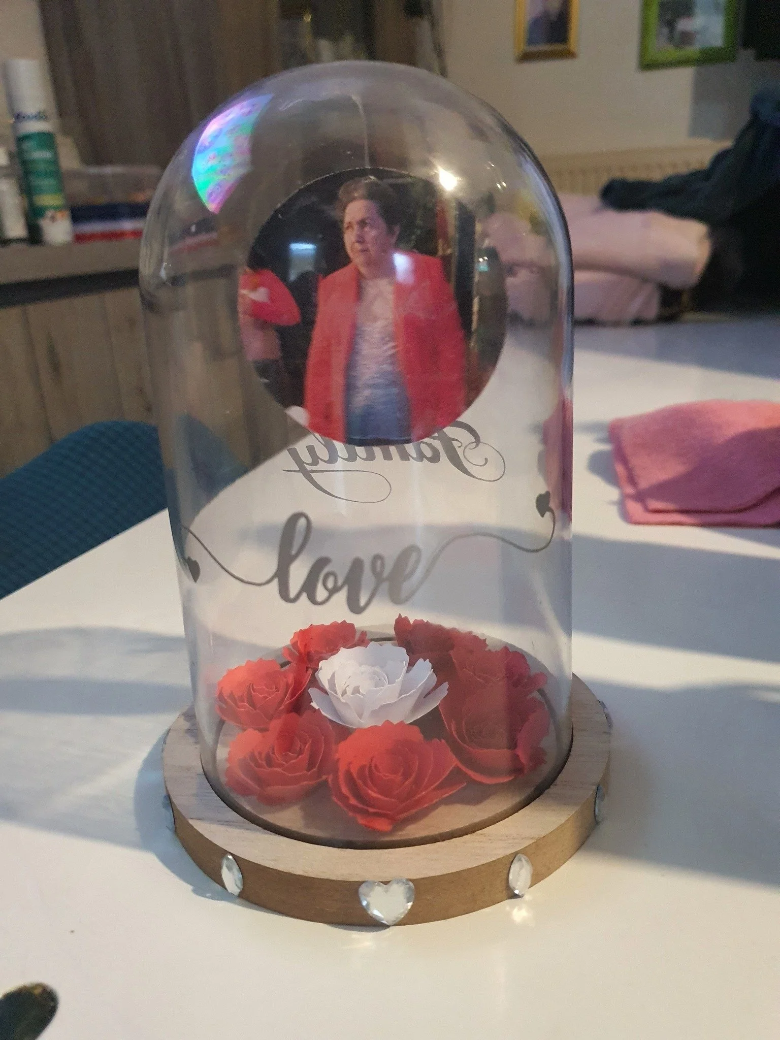 Une décoration avec une photo d'une femme à l'intérieur d'une boule en verre, entourée de roses rouges et blanches, avec le mot 'love' écrit sur la décoration