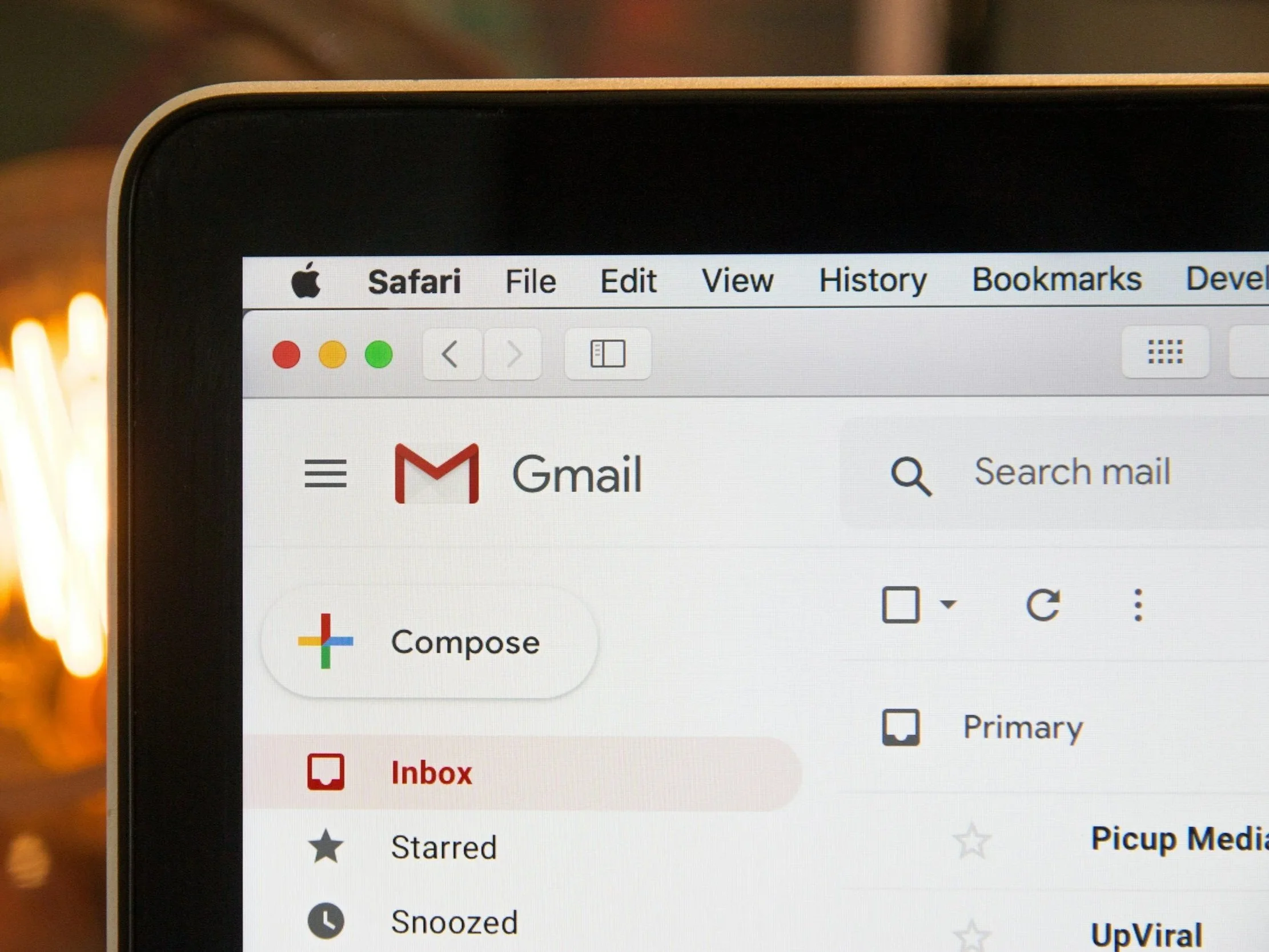 Close-up of a computer monitor screen showing an email inbox, with menu options like File, Edit, View, History, Bookmarks, and Dev in the browser toolbar, and the Gmail logo visible.