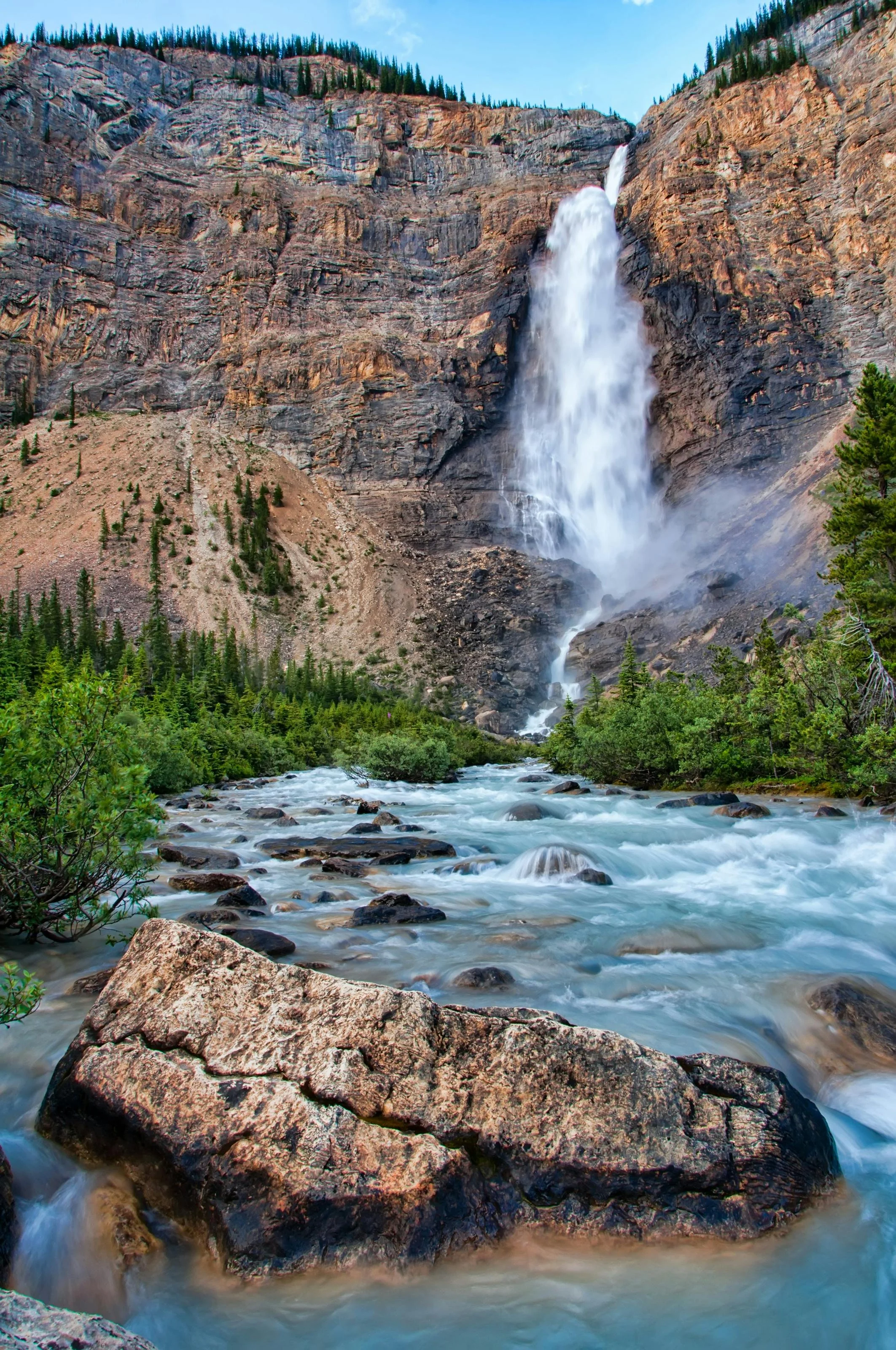 Water flowing from a waterfall with greenery and rock in the background.