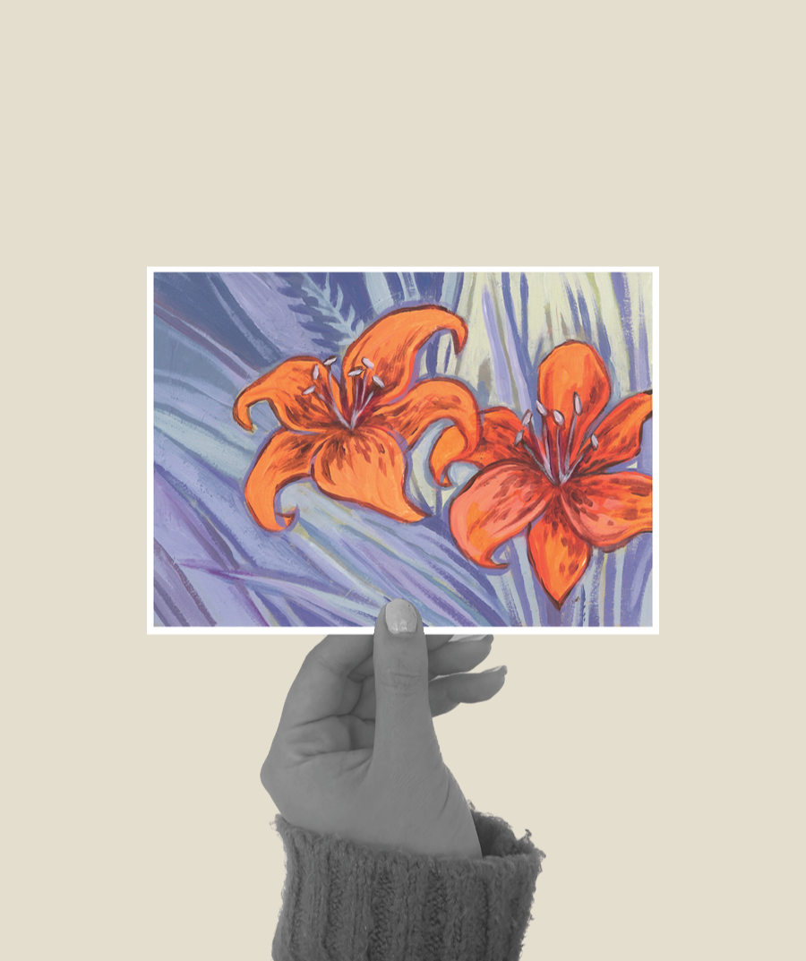 A hand holding a picture of painted orange lilies with purple and blue leaves in a watercolor style.