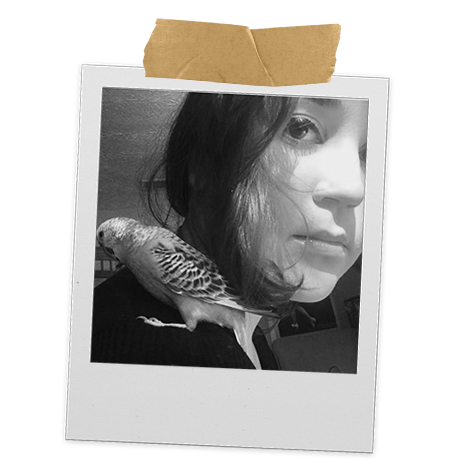 Black and white portrait photo of a woman with a bird perched on her shoulder, pinned to a wall with masking tape.